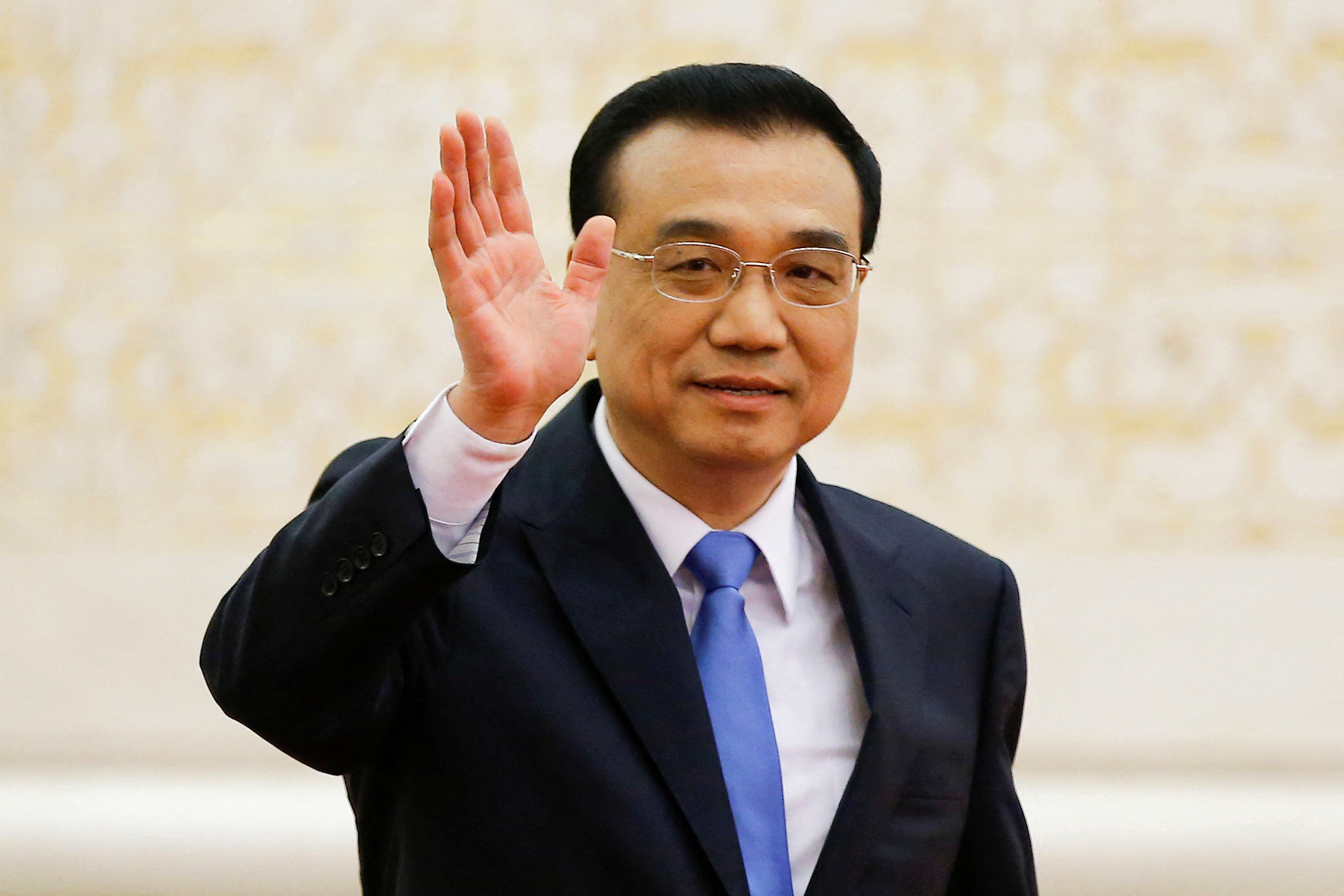 China's Premier Li Keqiang waves as he arrives for a news conference after the closing ceremony of China's National People's Congress (NPC) at the Great Hall of the People in Beijing