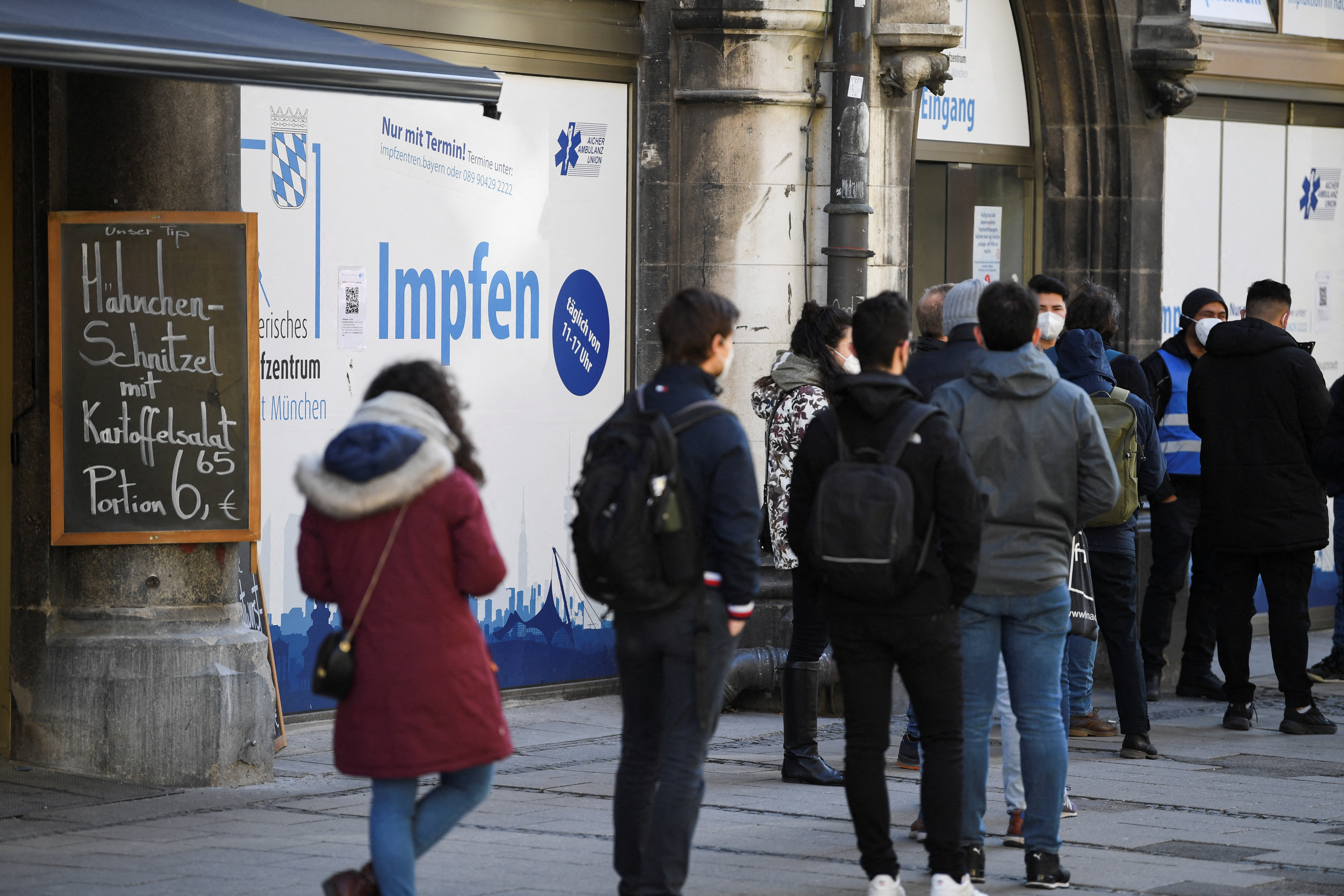 People wait in a line, for their vaccination against COVID-19, in front of a vaccination centre in Munich