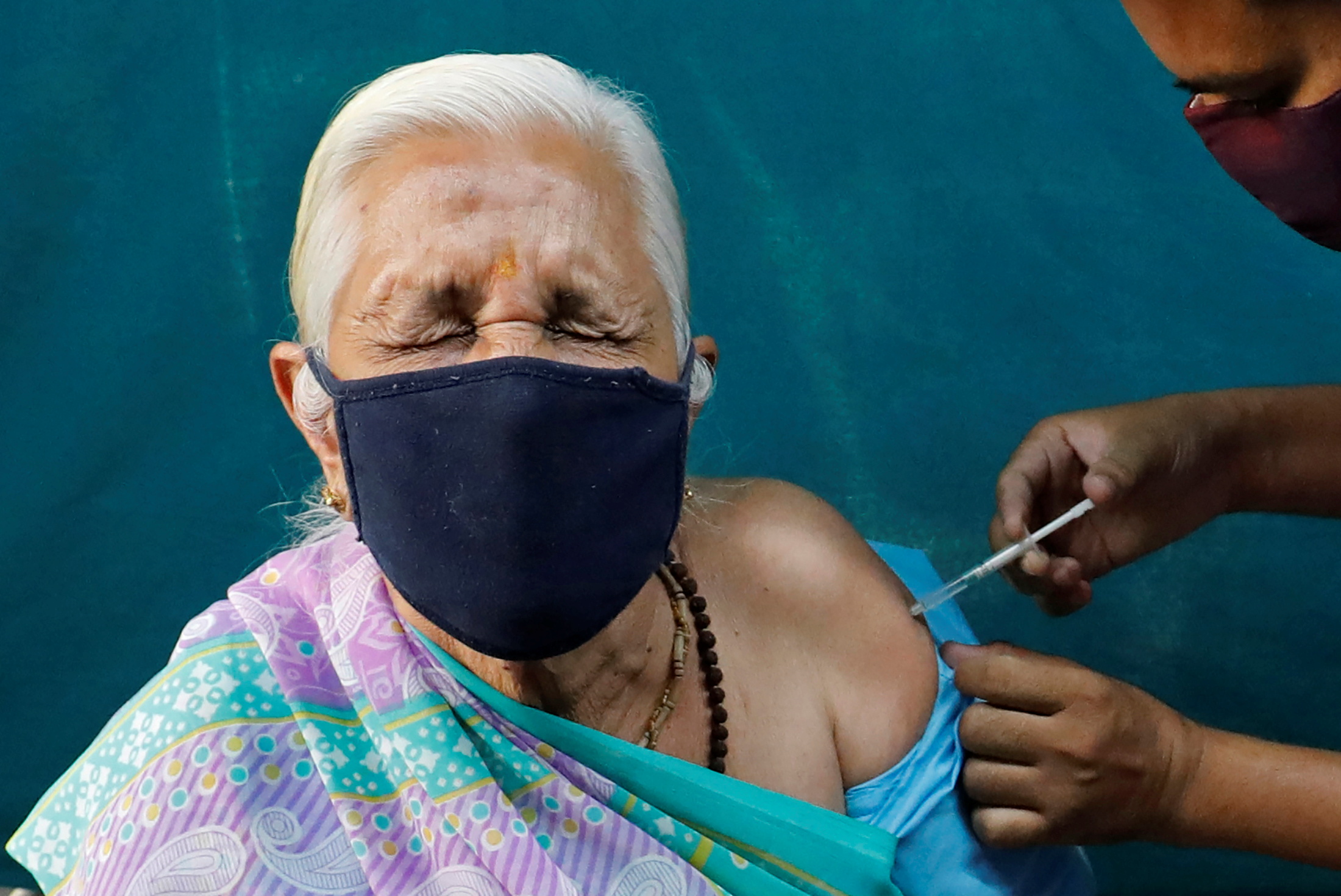 A woman reacts as she receives a dose of COVISHIELD, a coronavirus disease (COVID-19) vaccine, in Ahmedabad