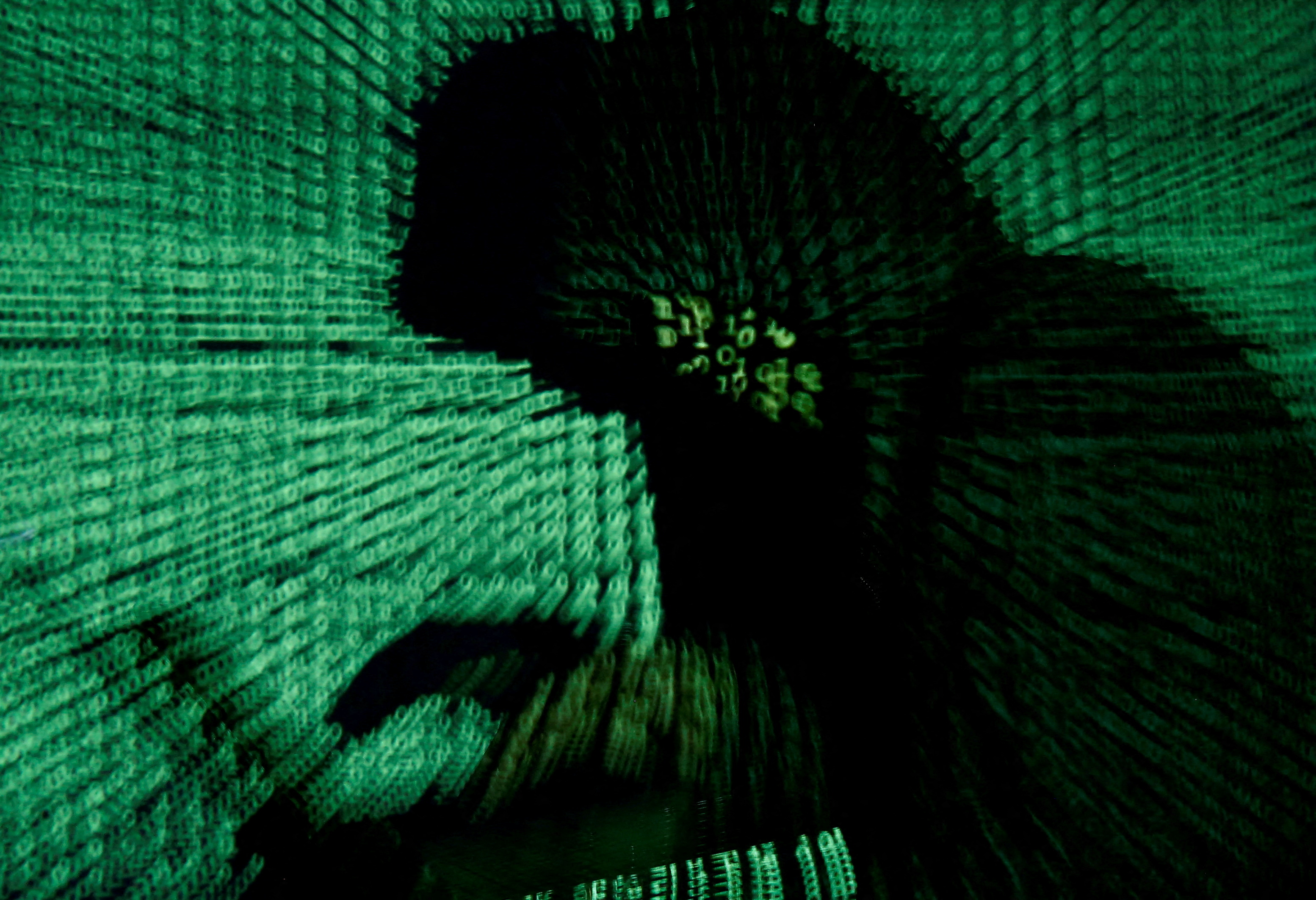 A man holds a laptop computer as cyber code is projected on him in this illustration picture taken on May 13, 2017. REUTERS/Kacper Pempel