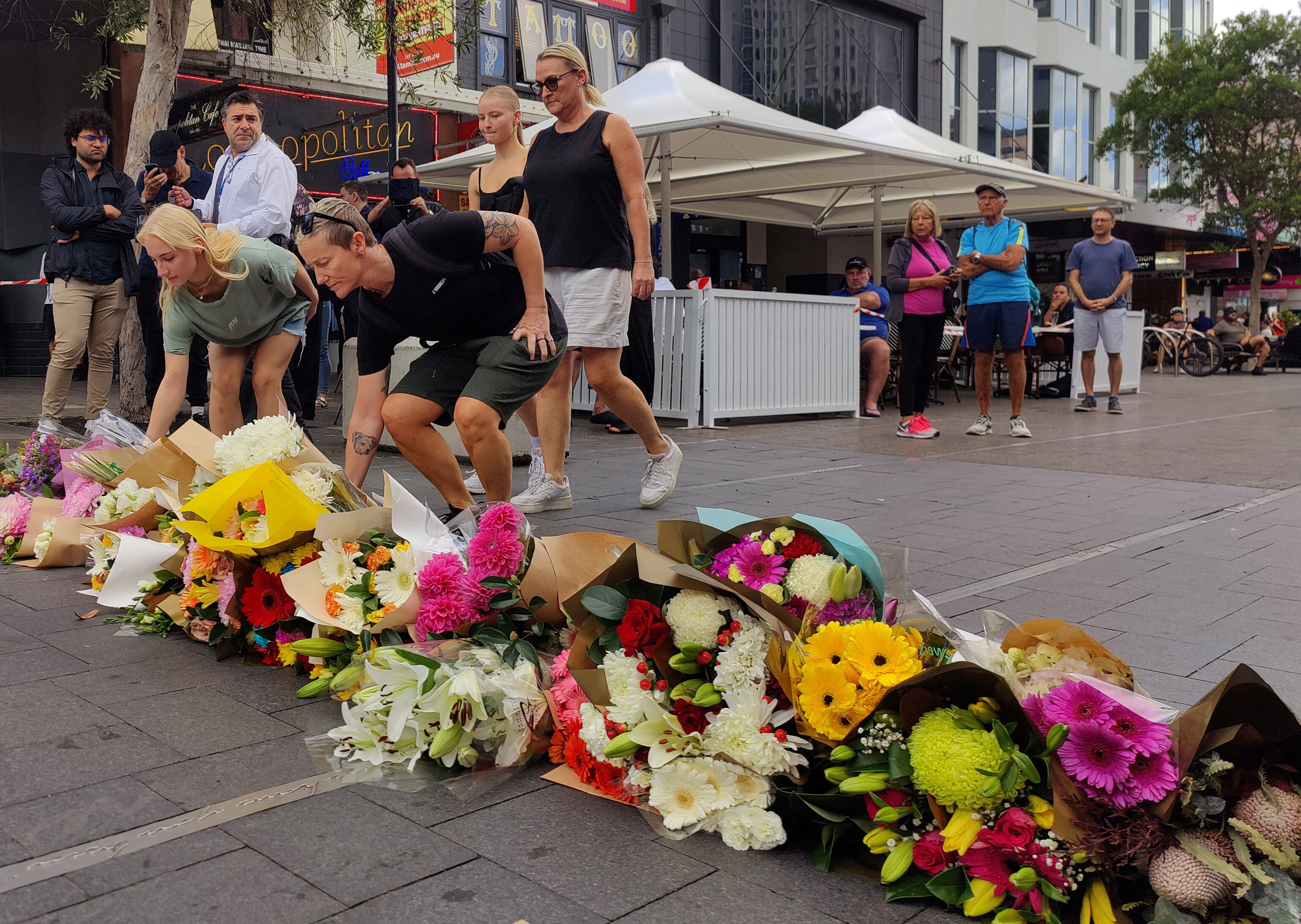 People offer flowers for the victims of Saturday's stabbings at Bondi Junction in Sydney
