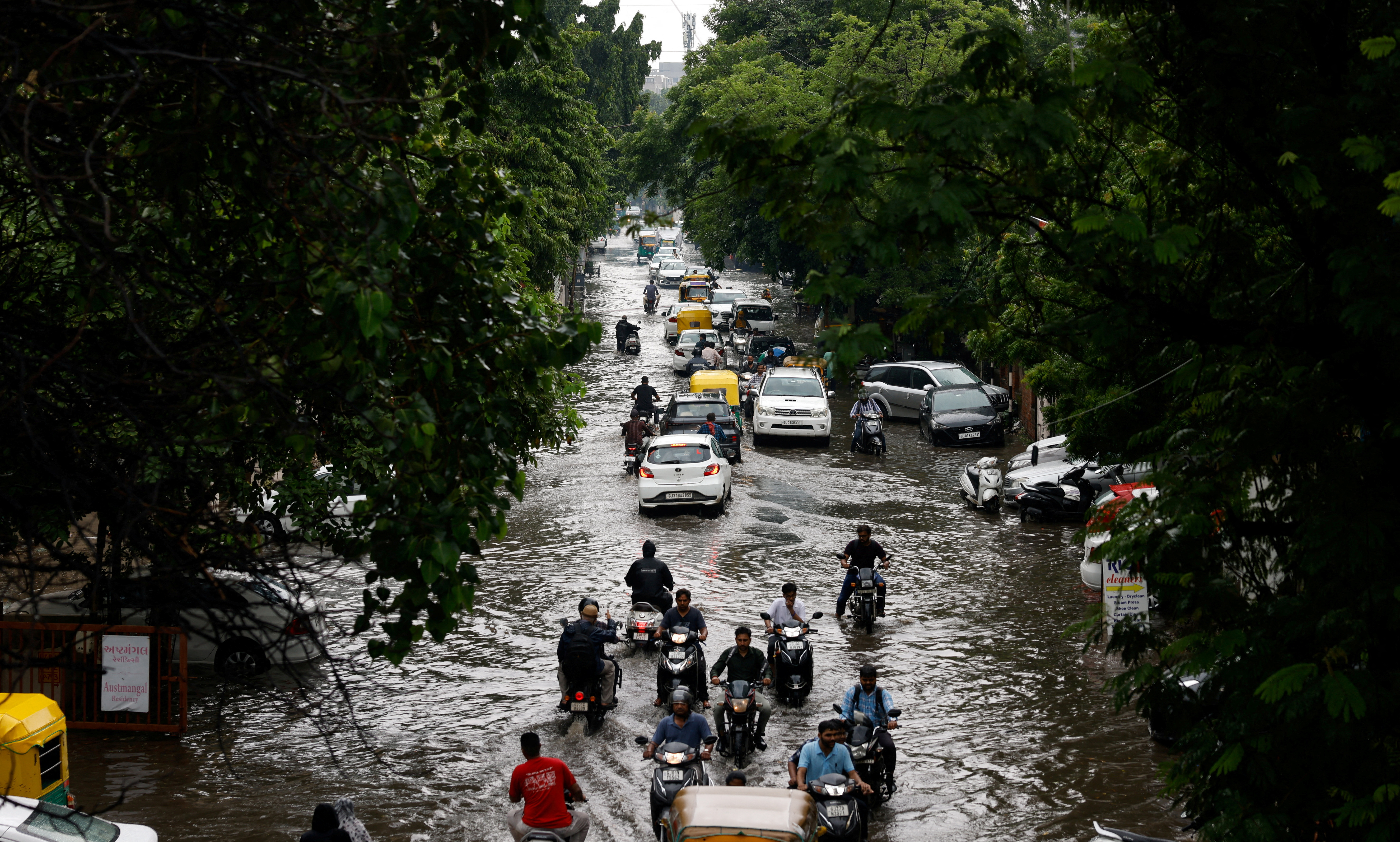 Traffic moves through a flooded road after heavy rains in Ahmedabad