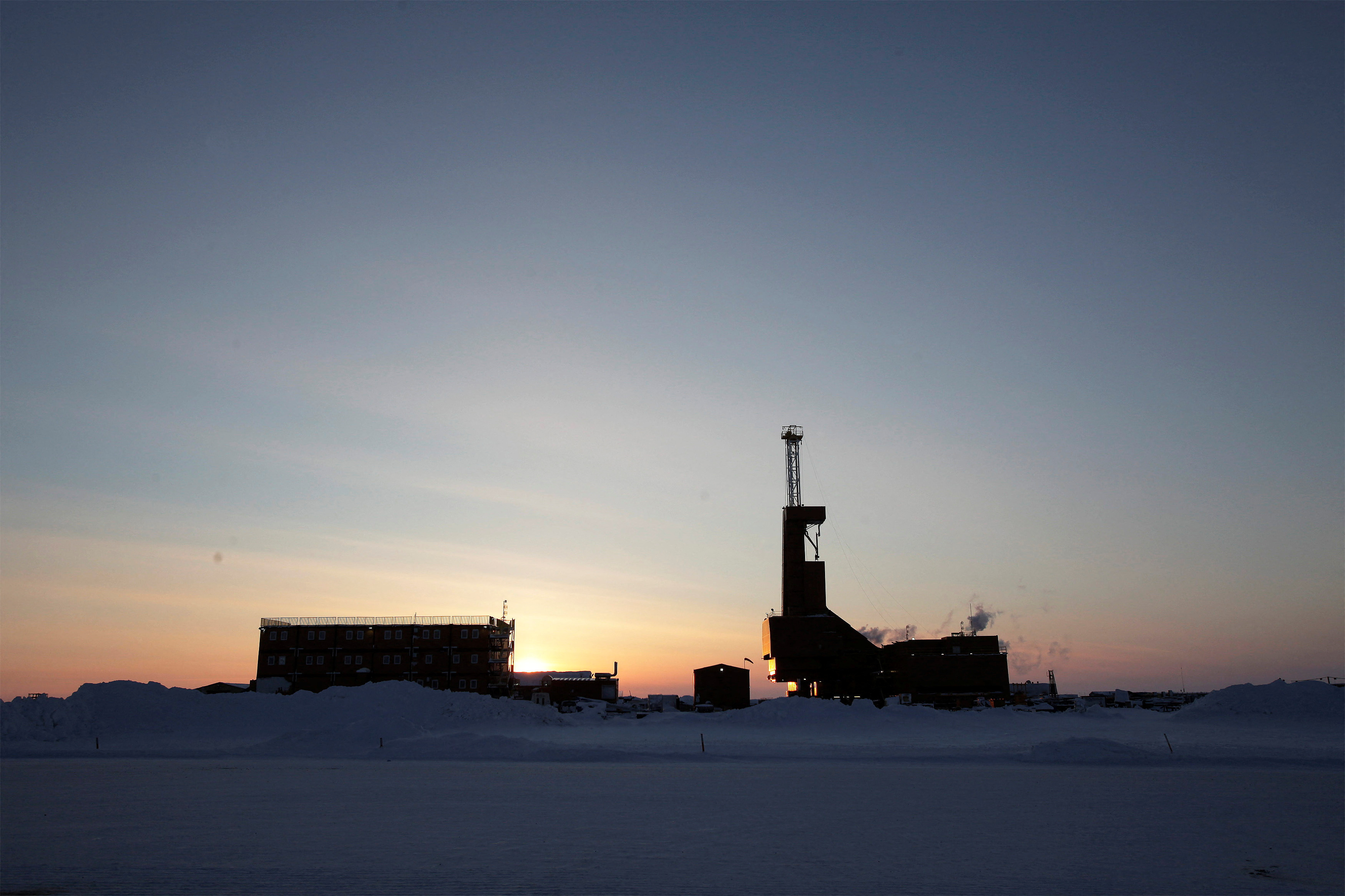 The sun sets behind an oil drilling rig in Prudhoe Bay, Alaska