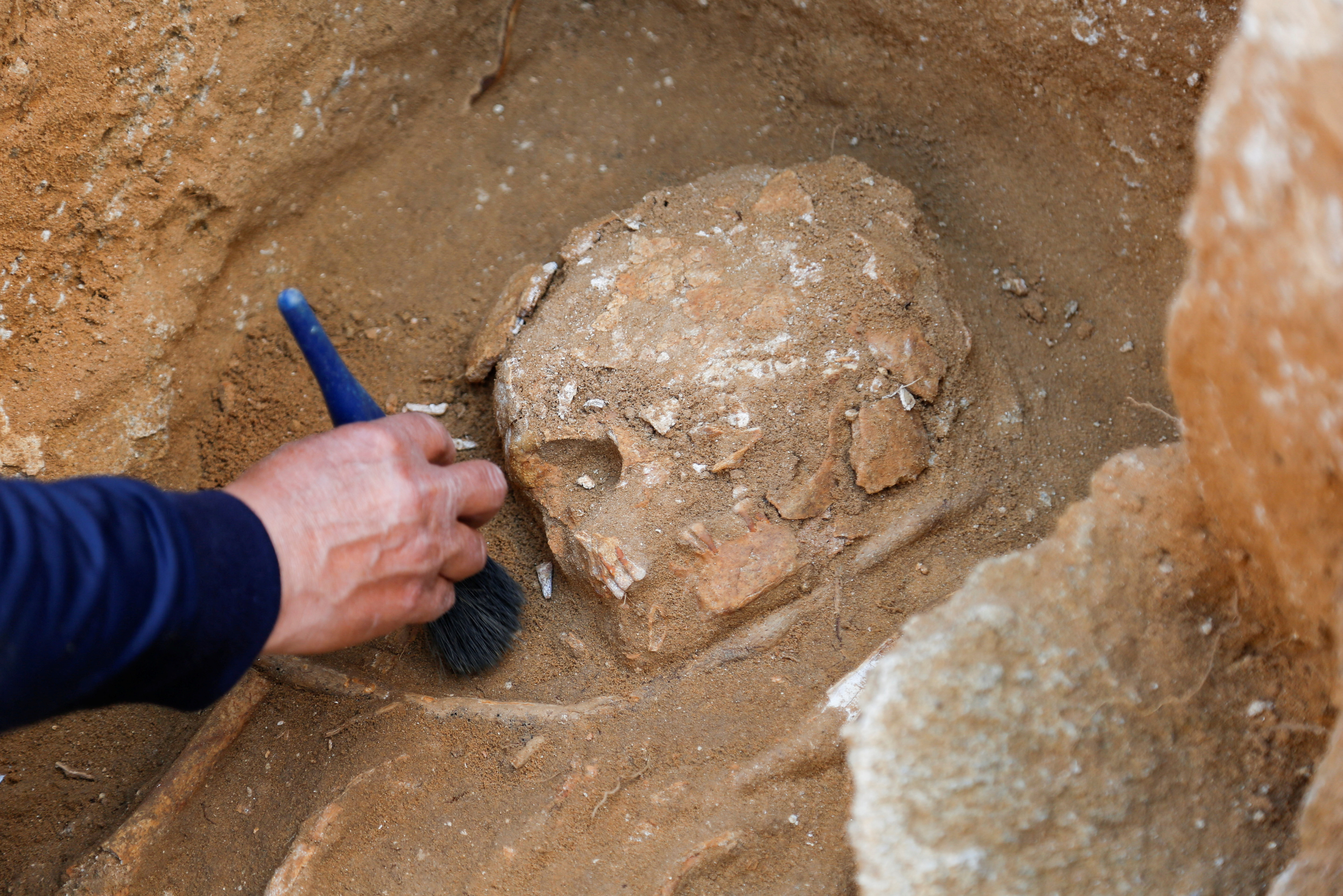 An archeology expert works on remains found in a grave at the site of a 2000-year-old Roman cemetery, that had been discovered last year,  in northern Gaza Strip
