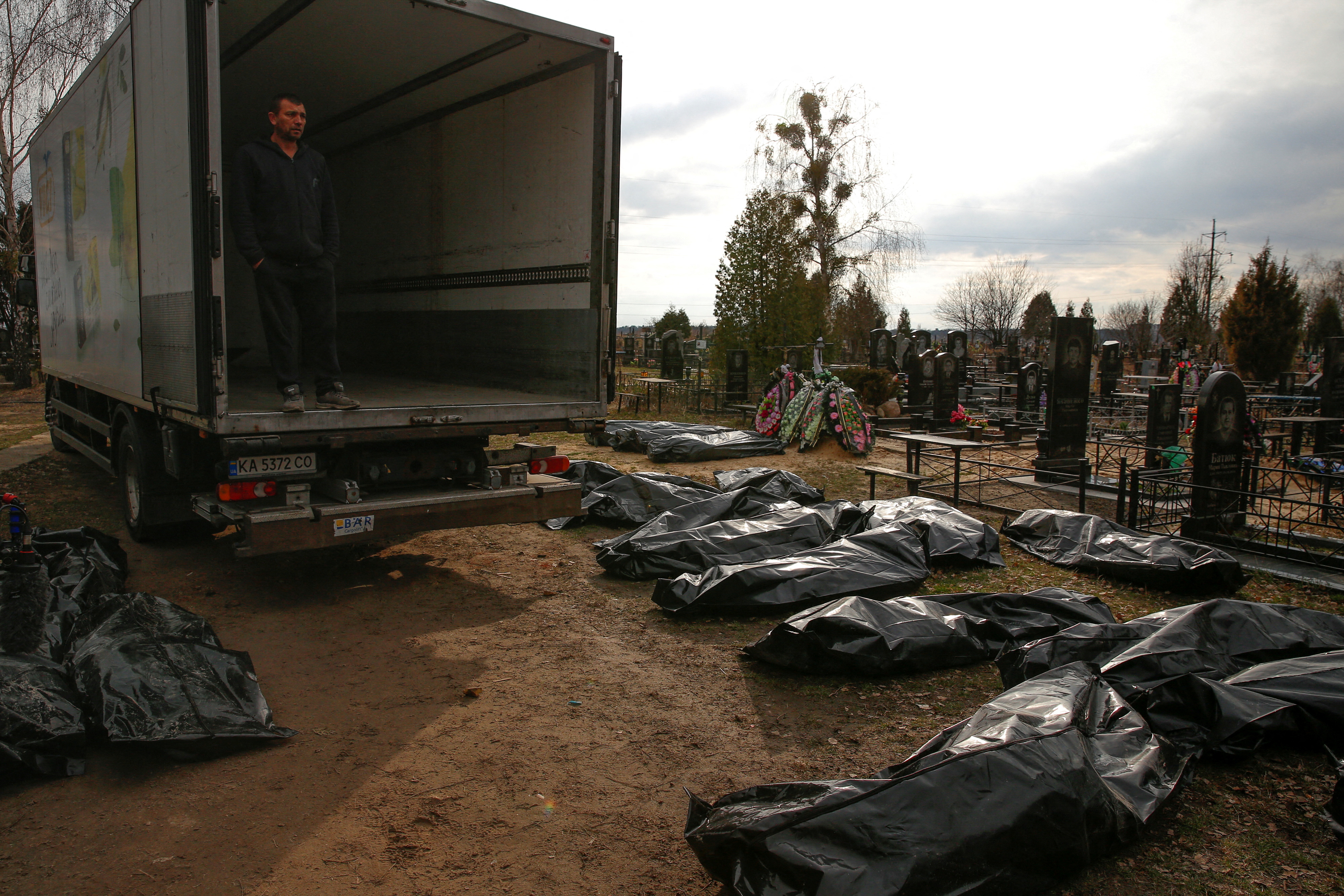 A funeral service employee looks at bodies of civilians, collected from streets to local cemetery, in the town of Bucha