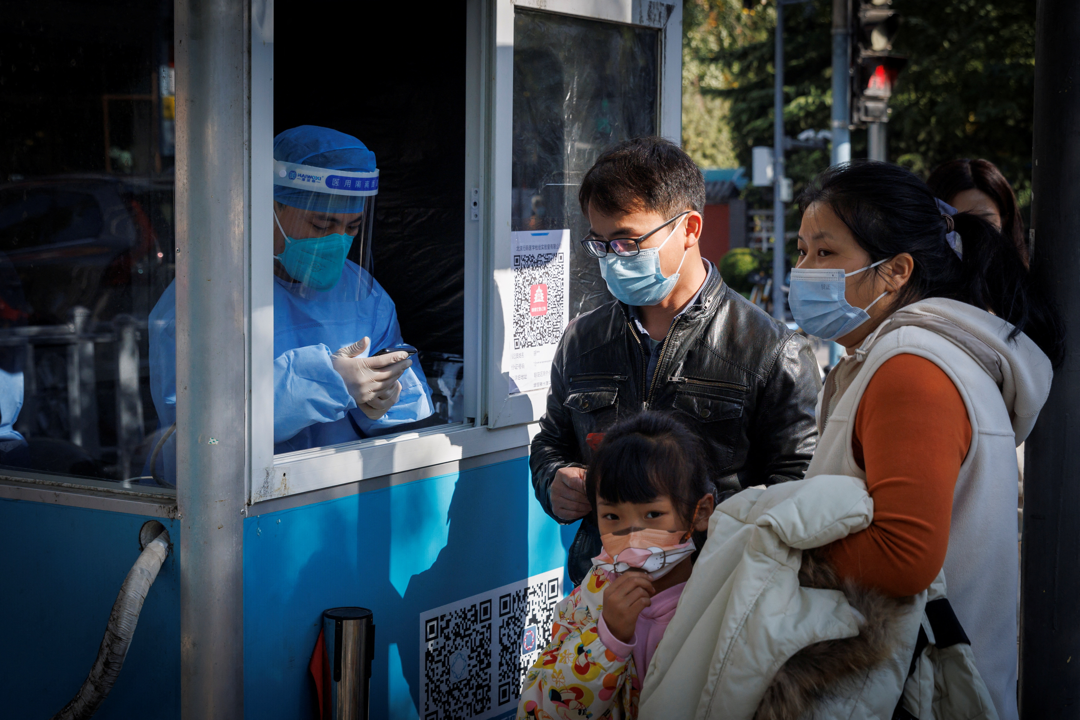 A pandemic prevention worker records personal details of people as they line up to get a swab test at a testing booth as outbreaks of coronavirus disease (COVID-19) continue in Beijing