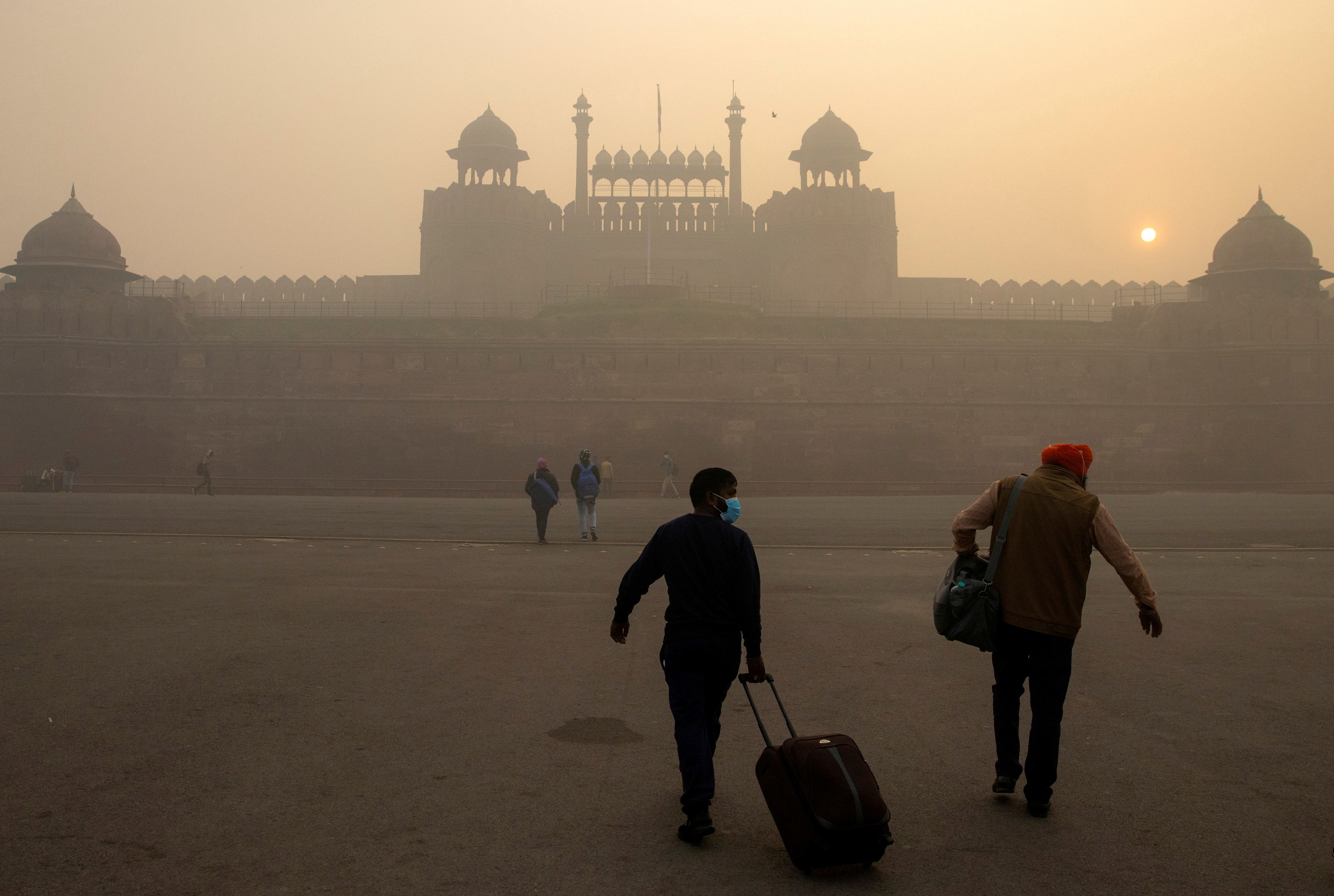 People arrive to visit the Red Fort on a smoggy morning in the old quarters of Delhi