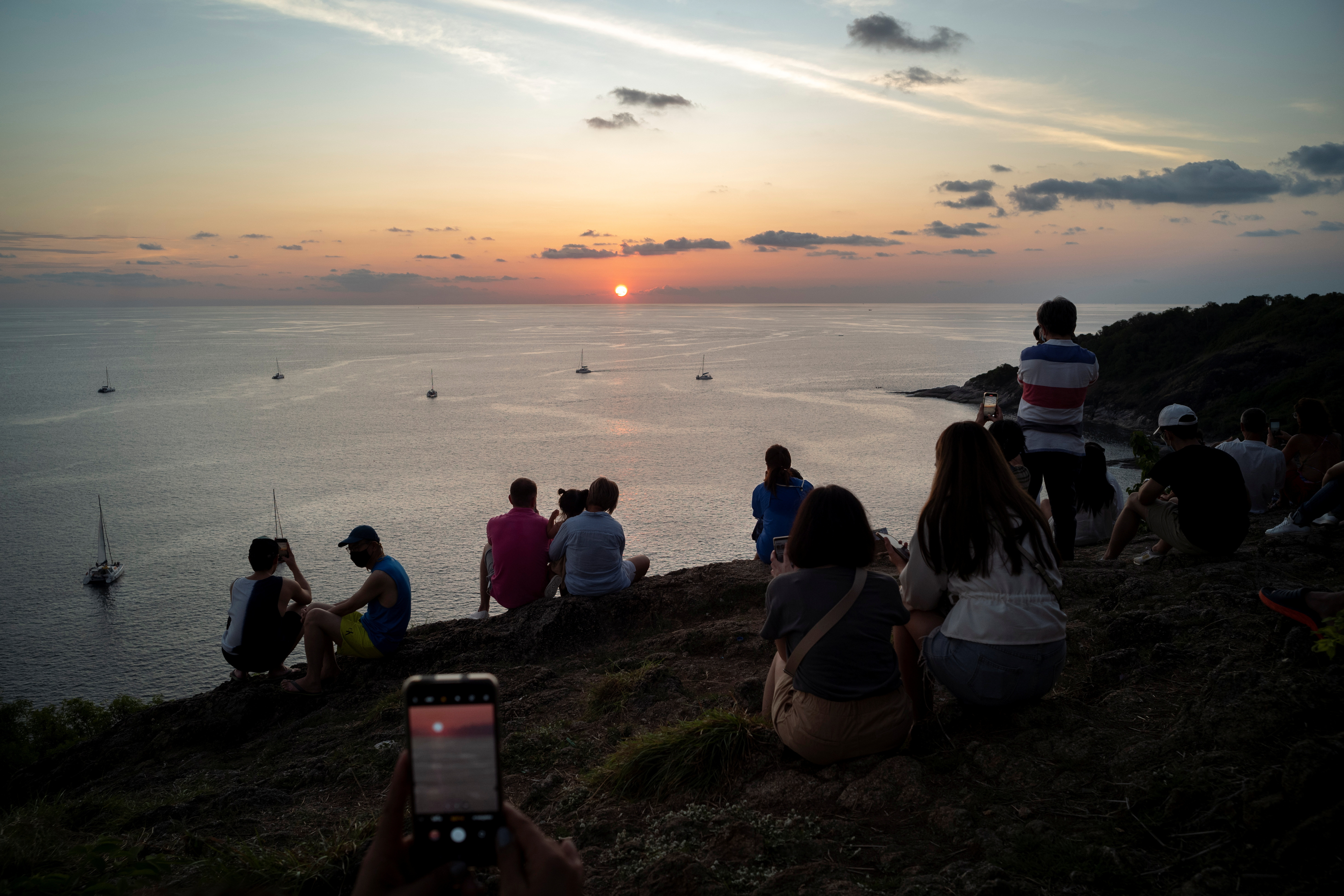 Locals and tourists watch a sunset from Phuket Island's Phromthep Cape
