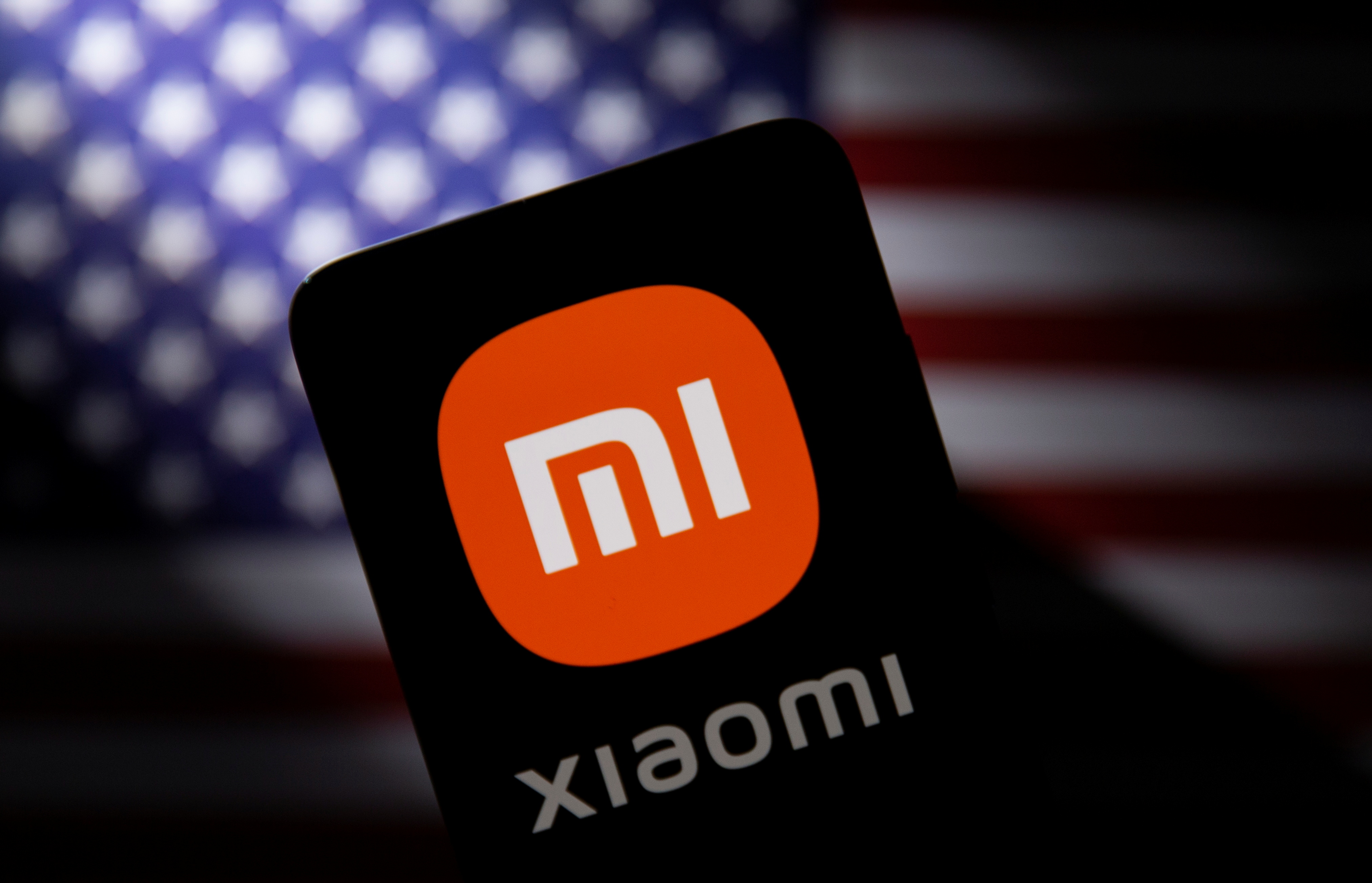Smartphone with a Xiaomi logo is seen in front of U.S. flag in this illustration