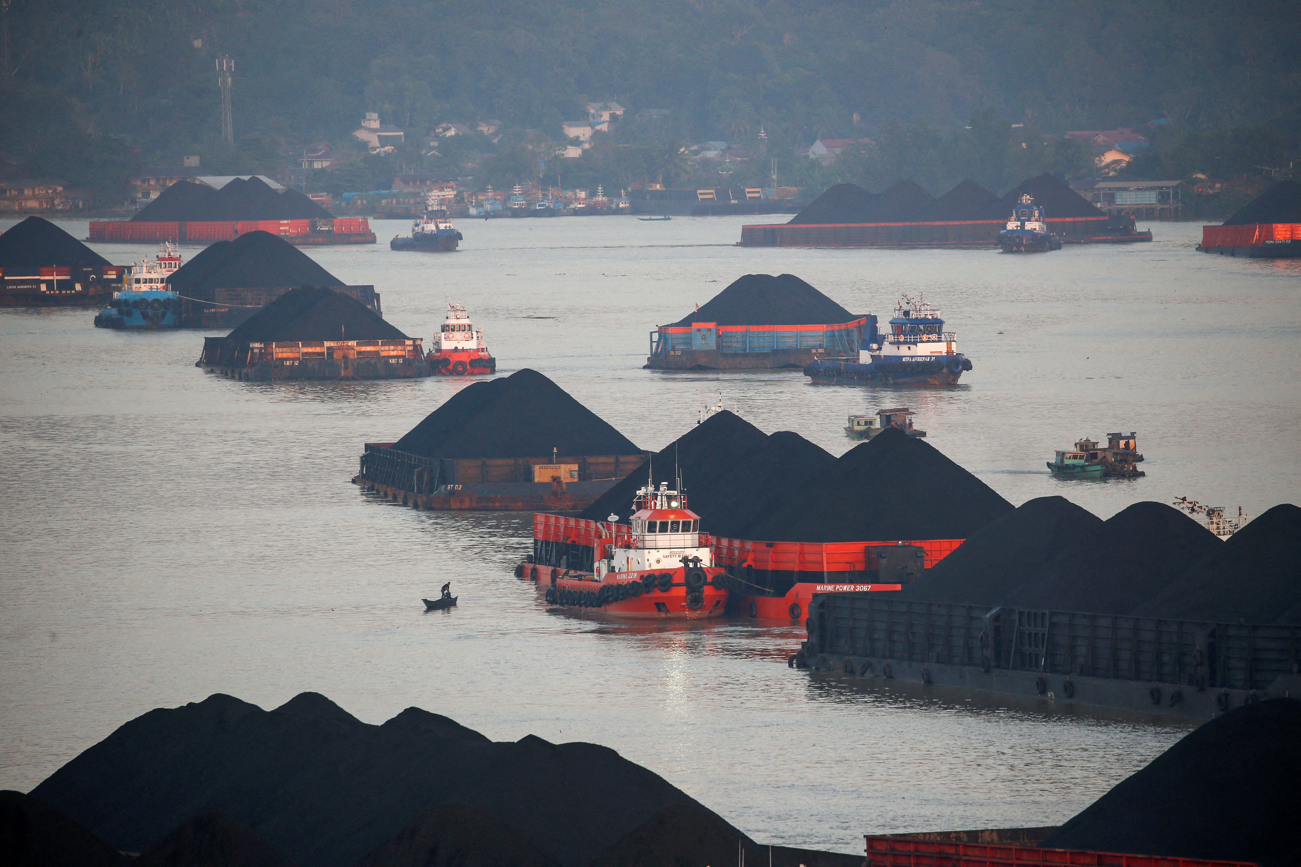 Coal barges are pictured as they queue to be pulled along Mahakam river in Samarinda