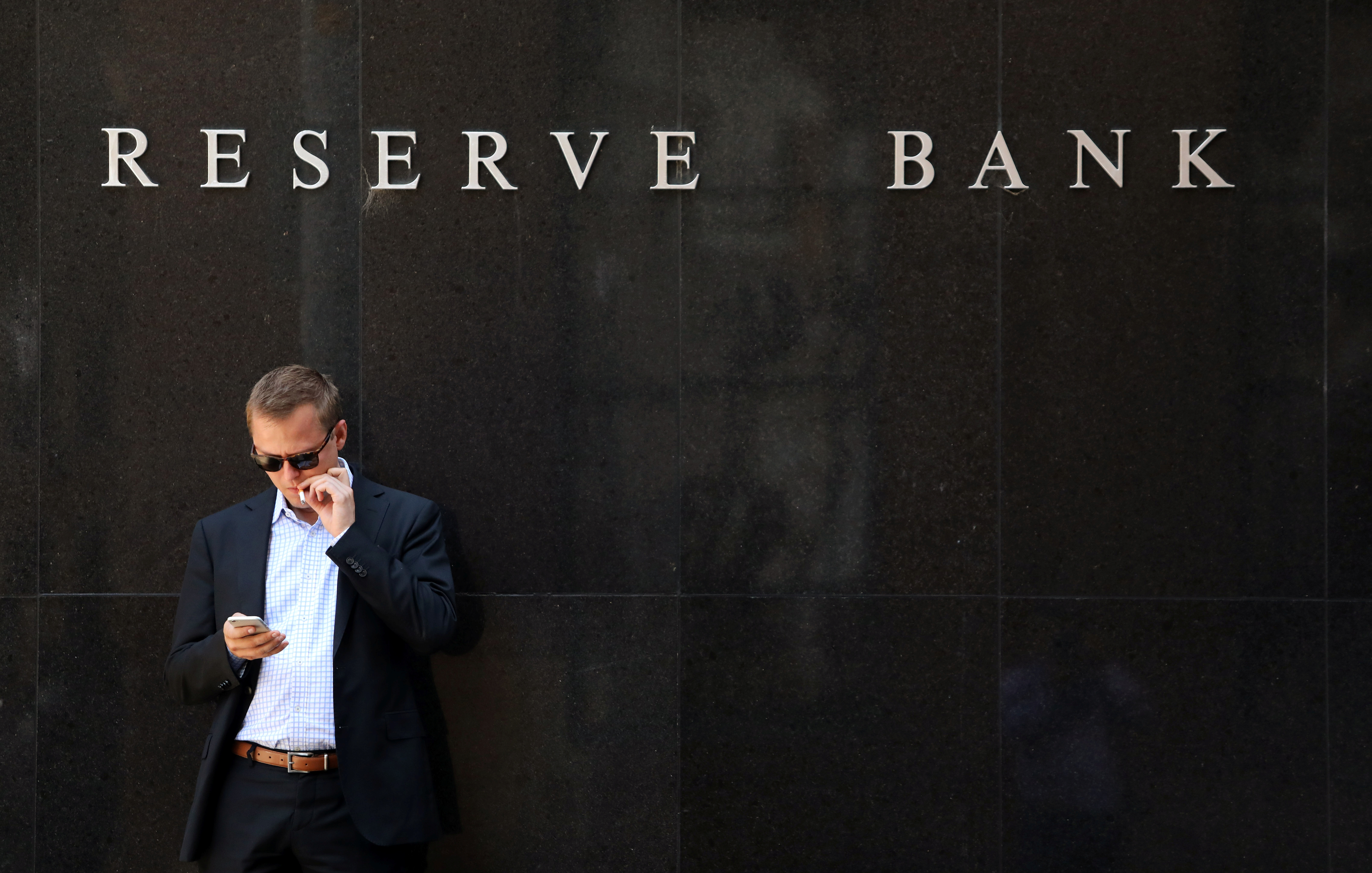 A man smokes next to the Reserve Bank of Australia headquarters in central Sydney