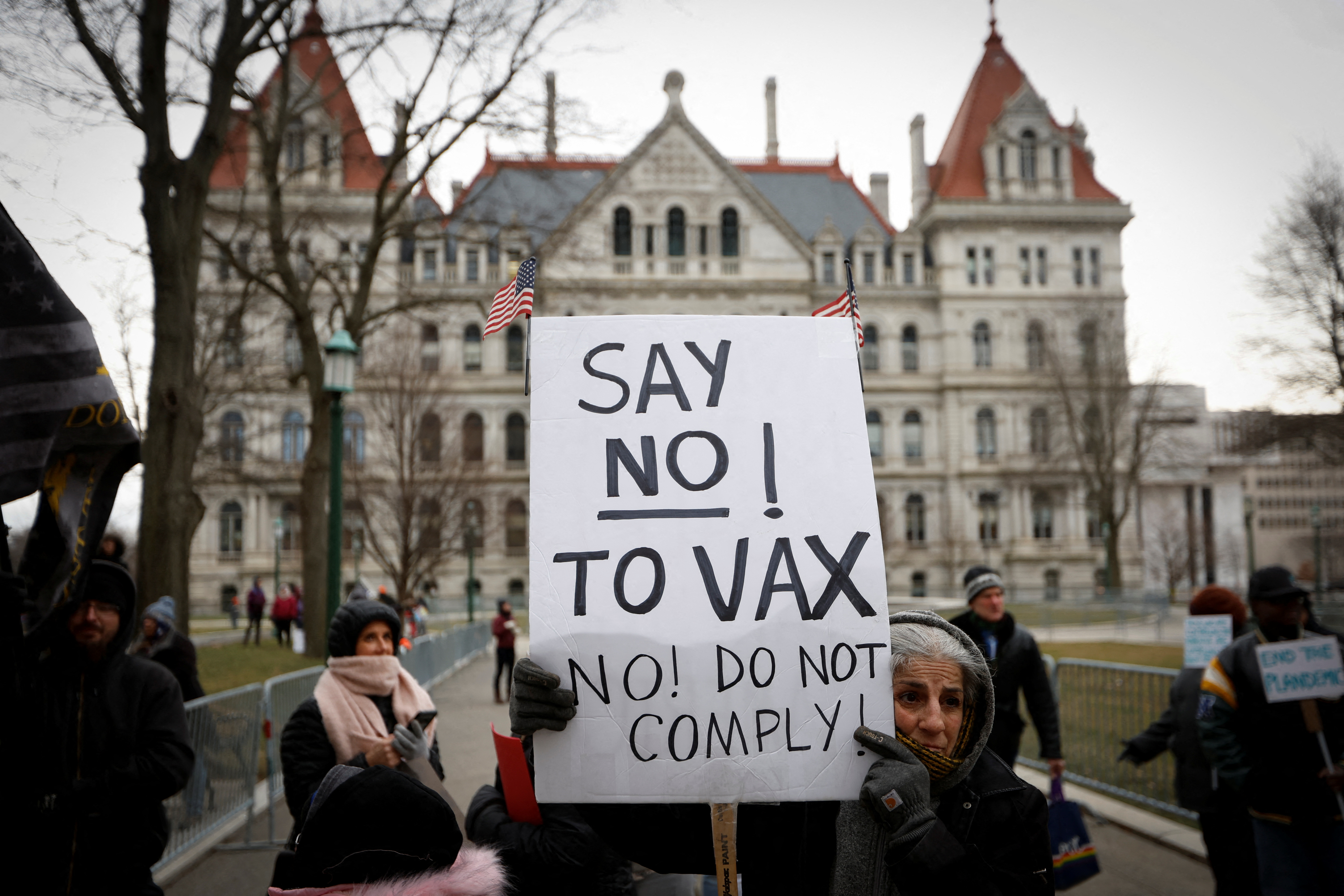 A protester holds a banner at a rally against mandates for the vaccines against the coronavirus disease (COVID-19) outside the New York State Capitol in Albany, New York, U.S., January 5, 2022. REUTERS/Mike Segar