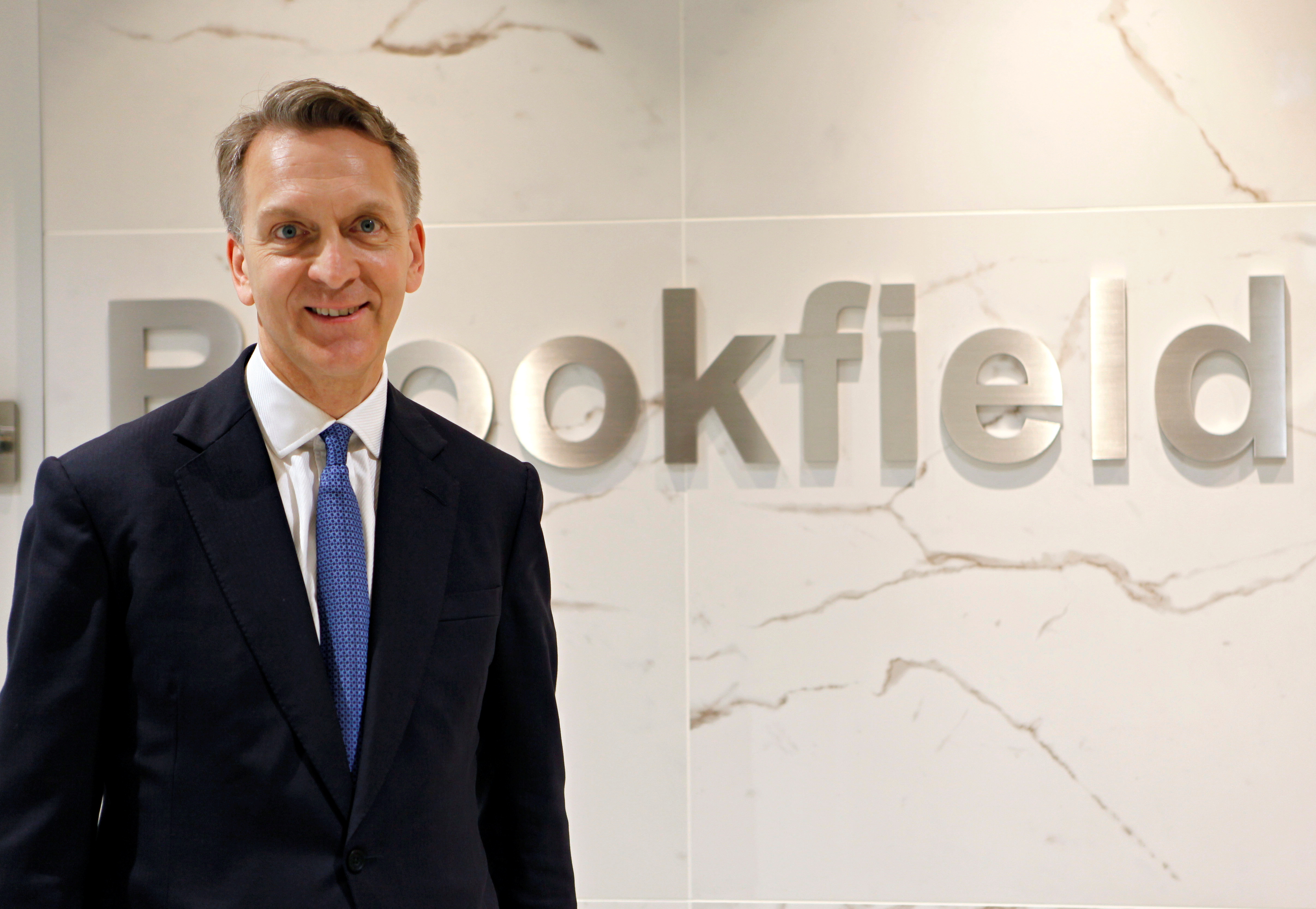 Bruce Flatt, CEO of Brookfield Asset Management, poses in front of the company's logo in Tokyo