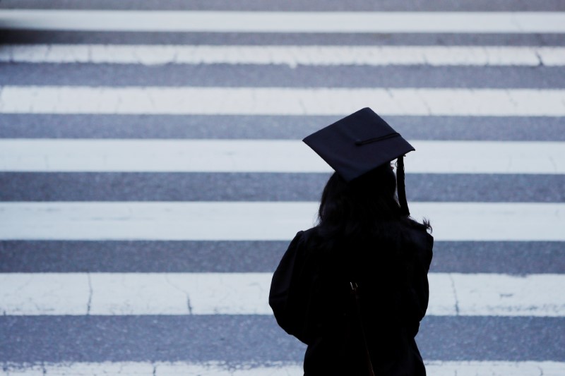 A graduating student waits to cross the street