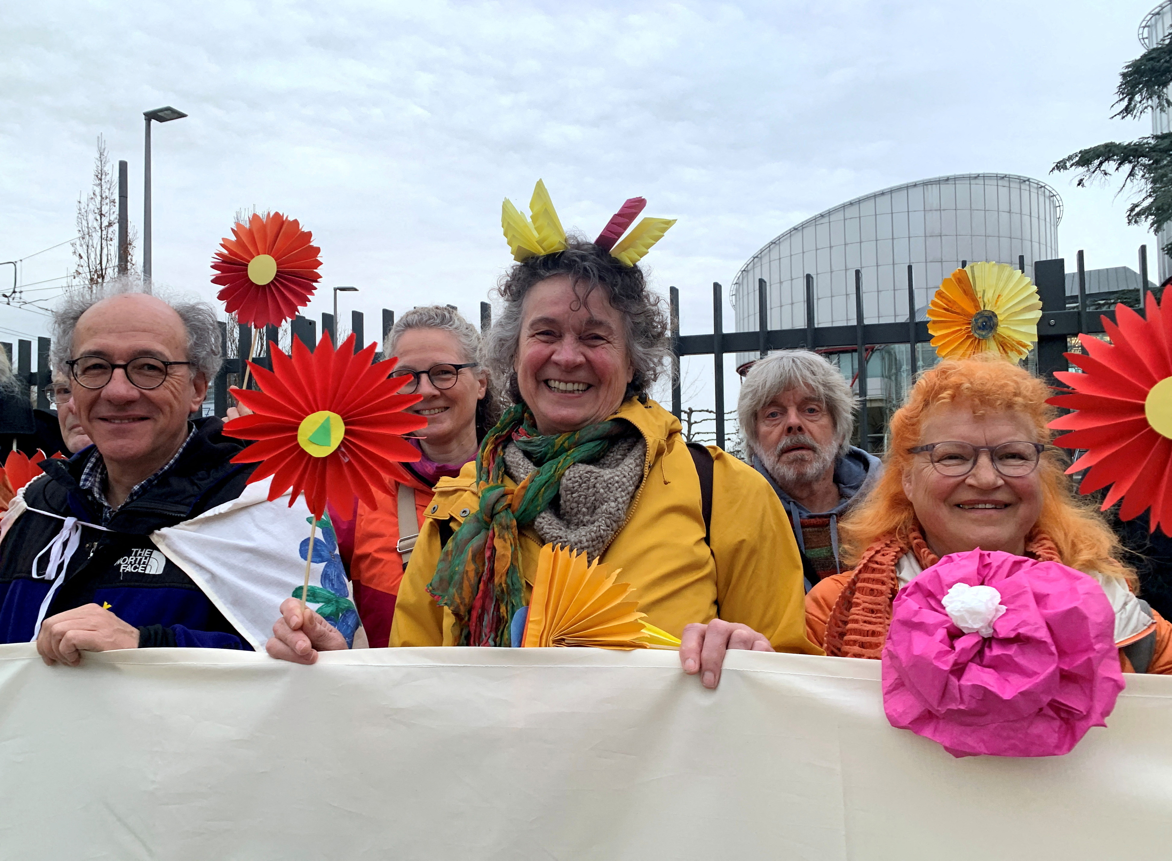 Supporters of the Senior Women for Climate Protection association hold paper flowers and a banner outside the European Court of Human Rights in Strasbourg