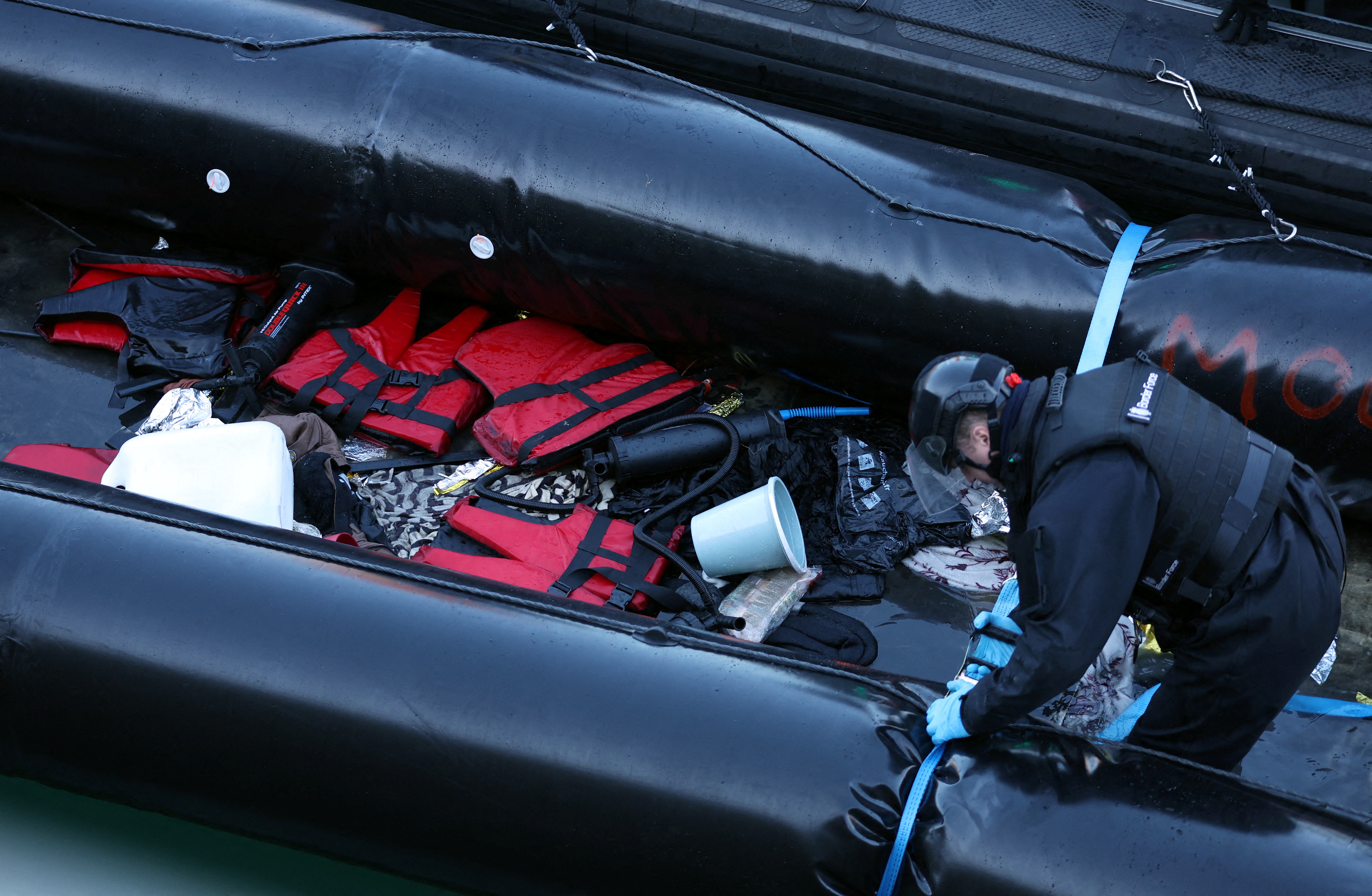 En anställd vid den brittiska gränsstyrkan inspekterar en jolle som används av migranter i Dovers hamn i Dover, Storbritannien, 14 januari 2022. REUTERS/Hannah McKay