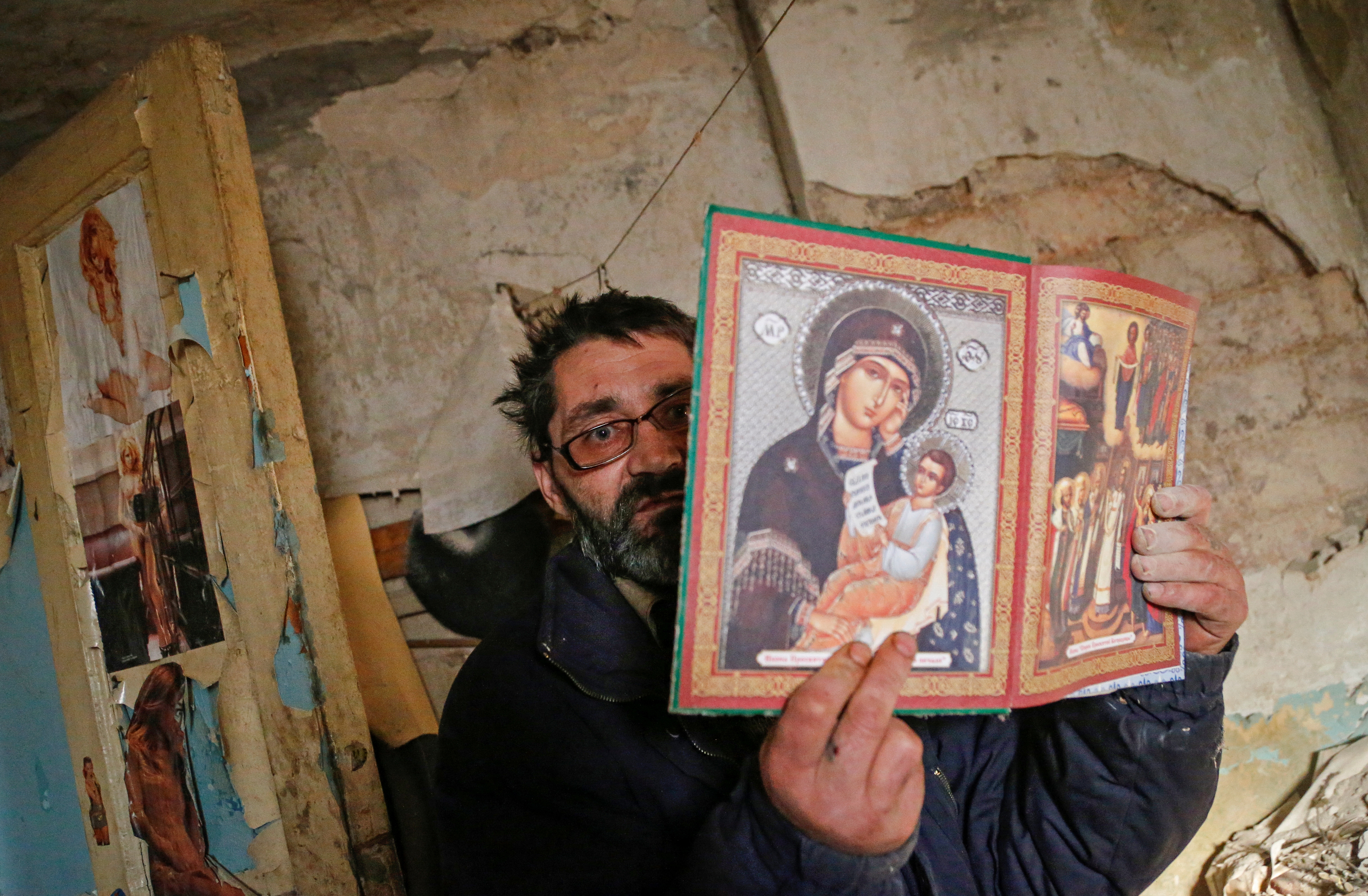 Local resident Aleksander Studenikin shows Orthodox icons inside his house, which was damaged by shelling, in Horlivka