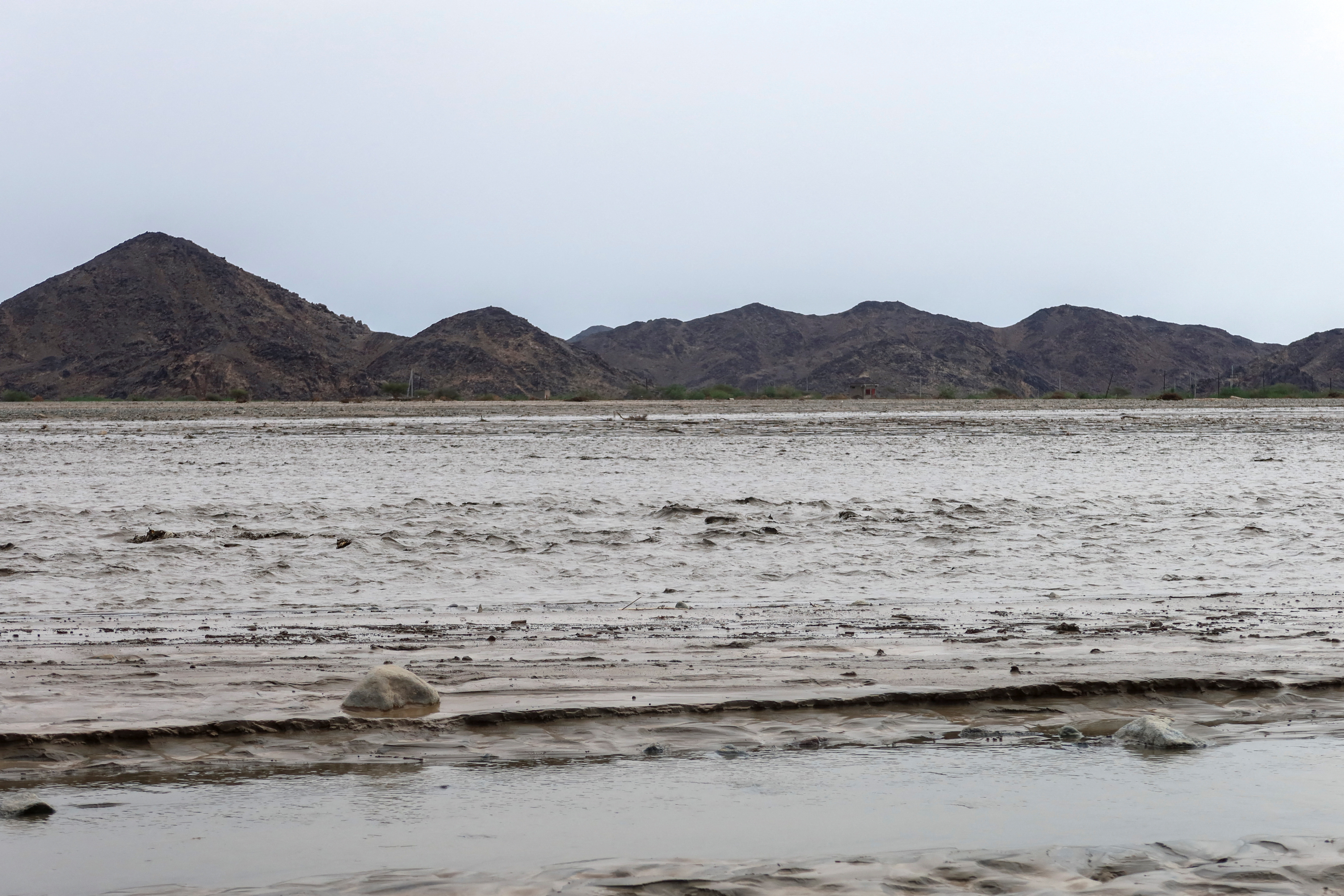 Flood water creates a channel, with the Red Sea mountains visible in the background, in Port Sudan