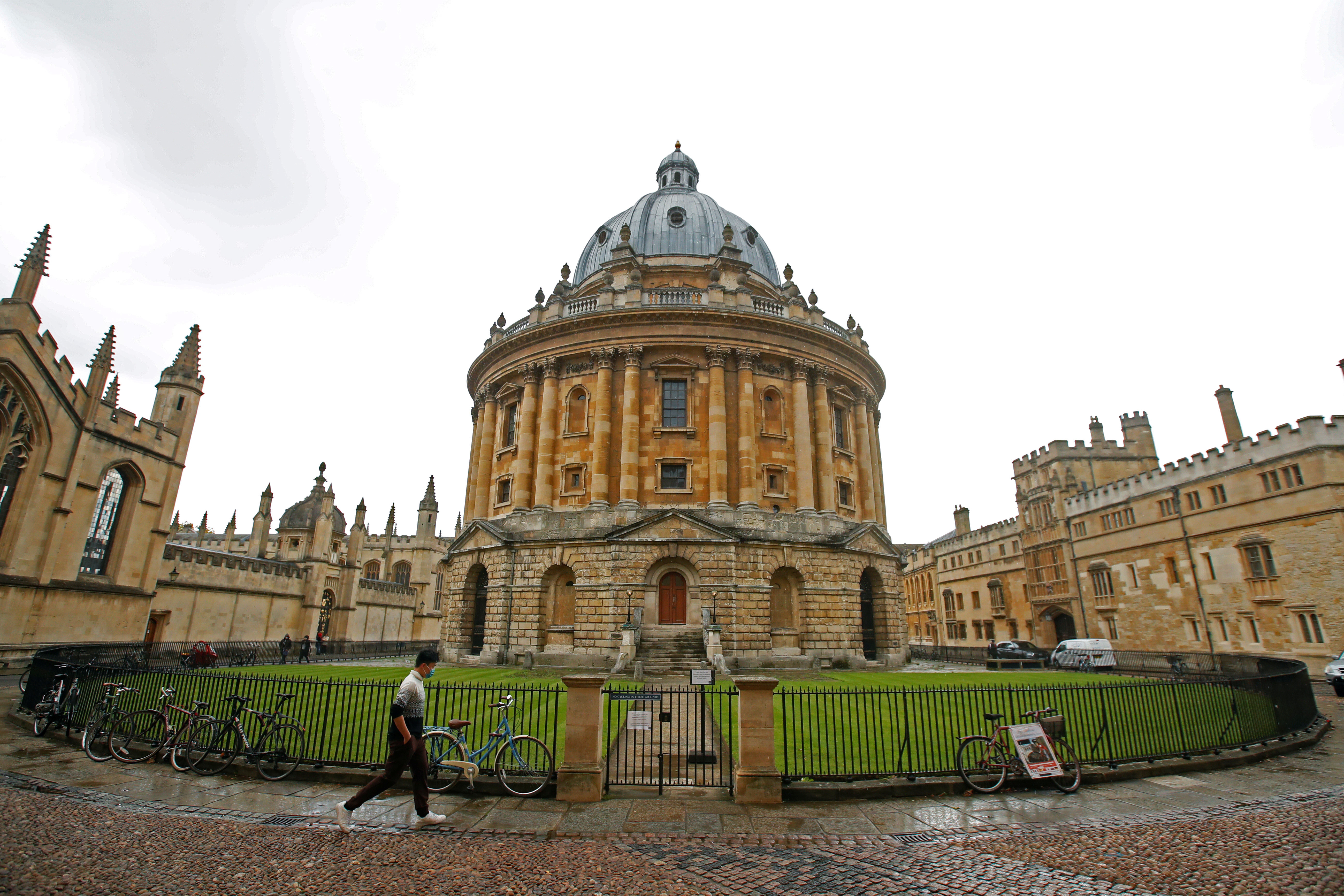 A man walks in front of the buildings of Oxford University