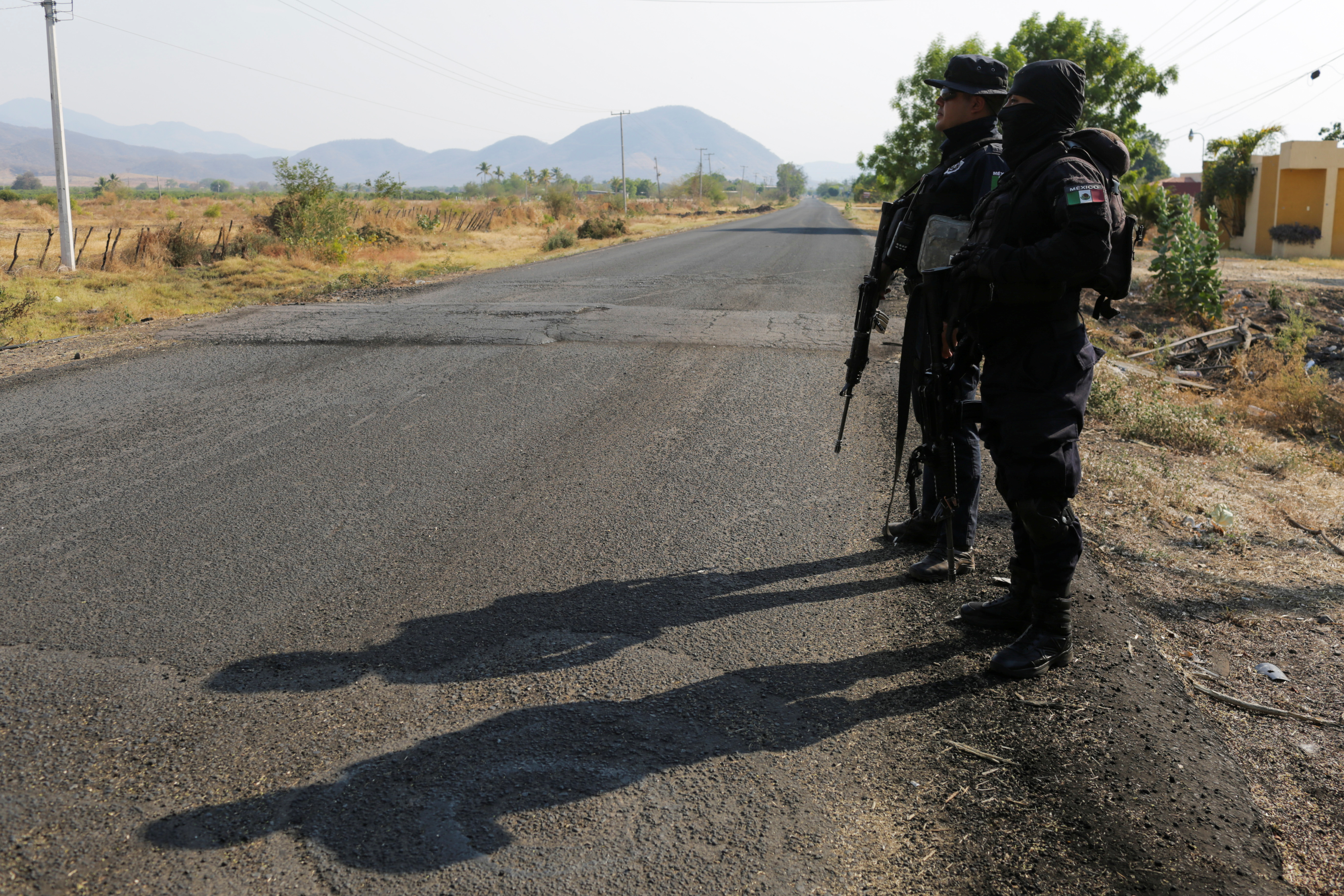 State police officers keep watch at a checkpoint in El Aguaje after the visit of Vatican's ambassador to Mexico Franco Coppola to the area and to the municipality of Aguililla, an area where the Jalisco New Generation Cartel (CJNG) and local drug gangs are fighting to control the territory, in Michoacan state, Mexico April 23, 2021. REUTERS/Alan Ortega