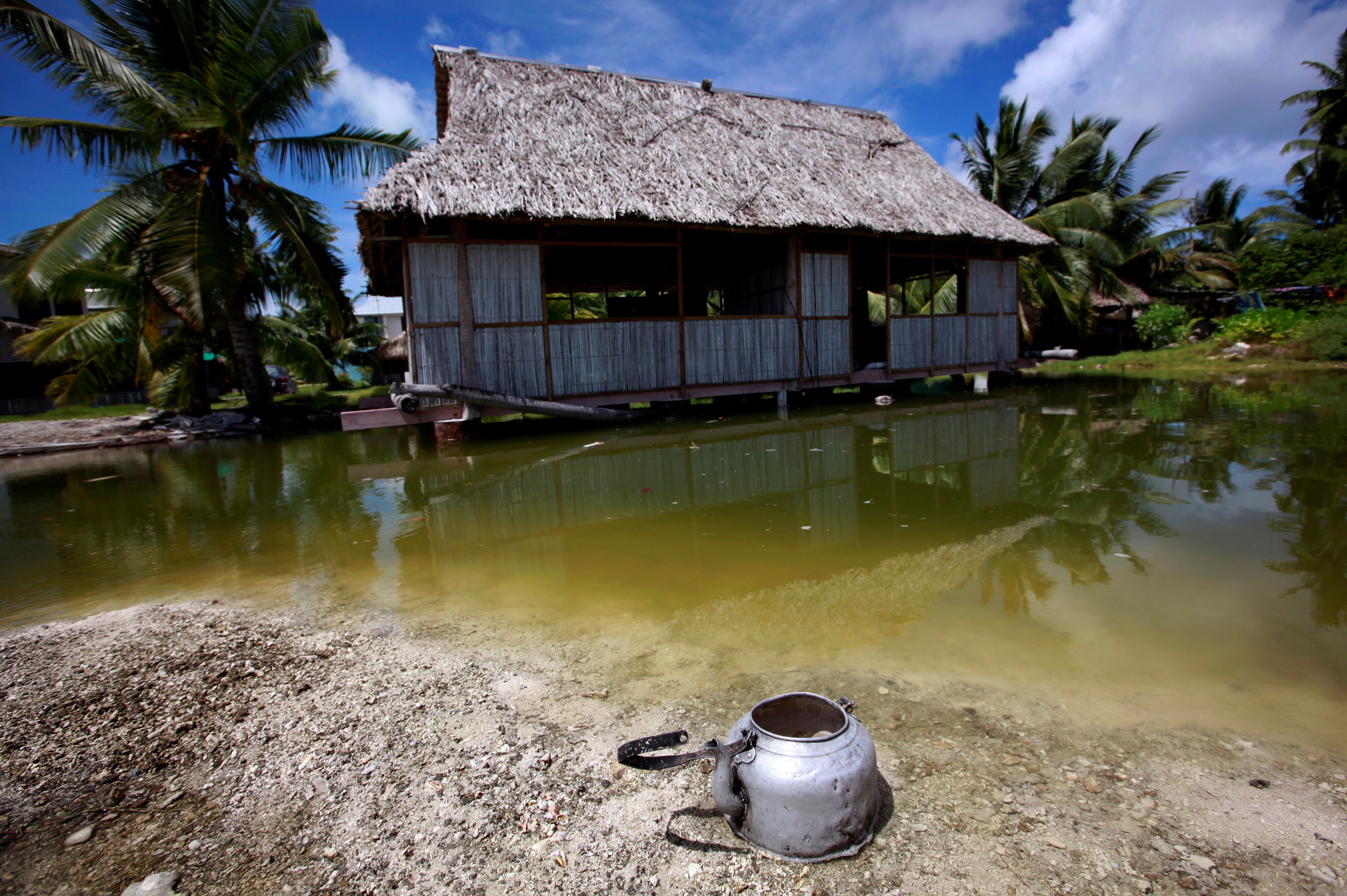 An abandoned house that is affected by seawater during high-tides stands next to a small lagoon near the village of Tangintebu on South Tarawa in the central Pacific island nation of Kiribati May 25, 2013. REUTERS/David Gray
