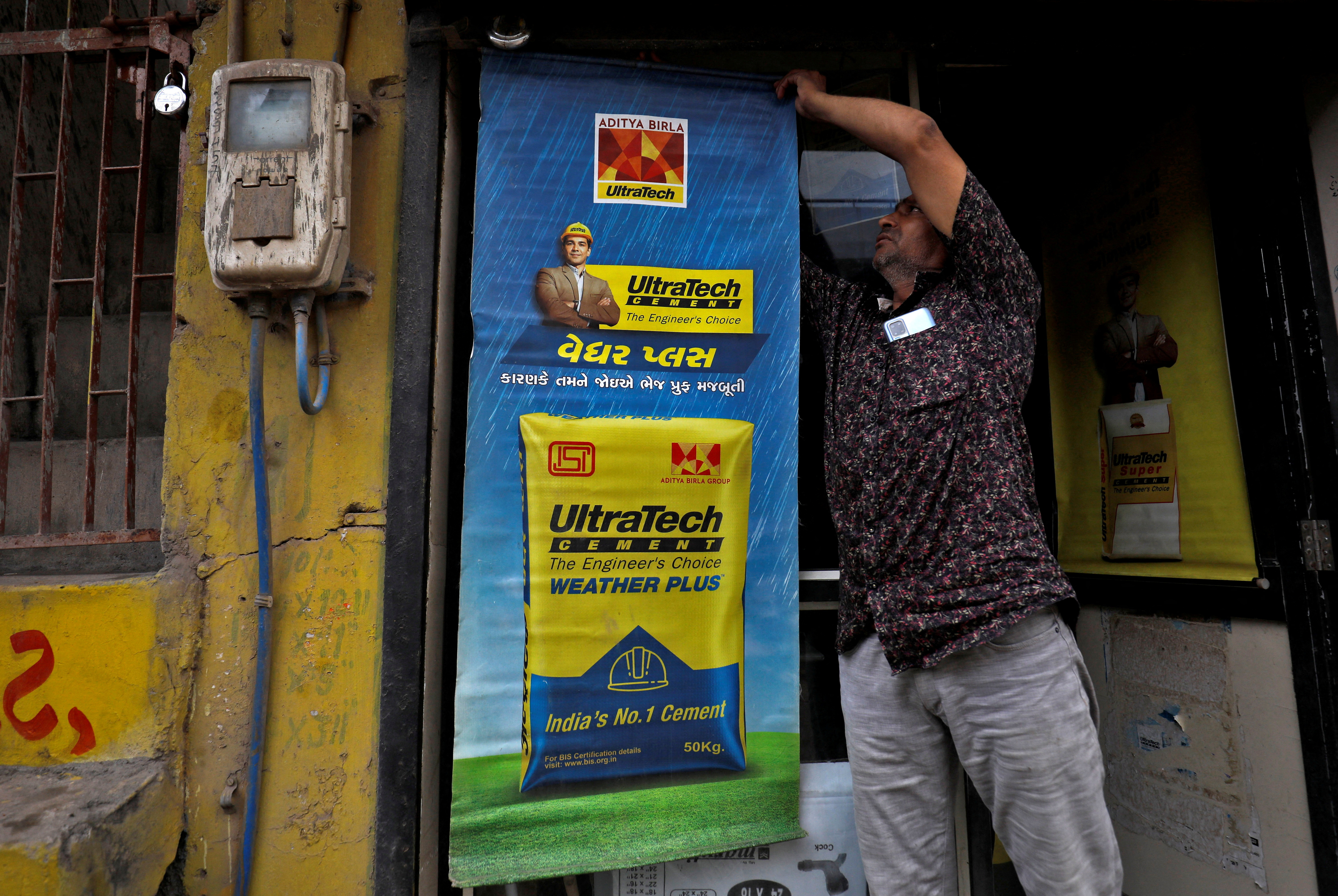 A man installs an UltraTech Cement billboard at his shop in Ahmedabad