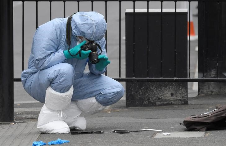 A forensics investigator photographs knives on the ground after man in Westminster after an arrest was made on Whitehall in central London