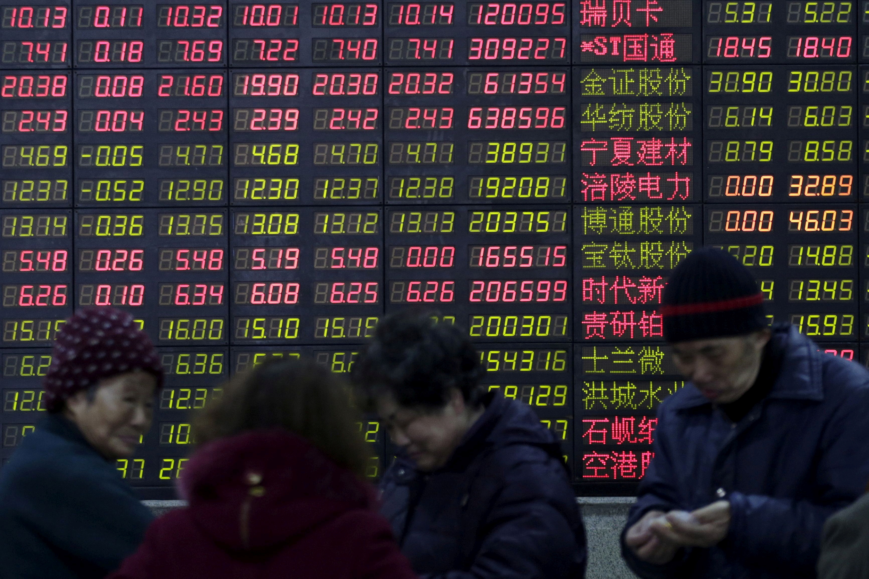 Investors stand in front of an electronic board showing stock information on the first trading day after the week-long Lunar New Year holiday at a brokerage house in Shanghai, China, February 15, 2016. REUTERS/Aly Song//File Photo