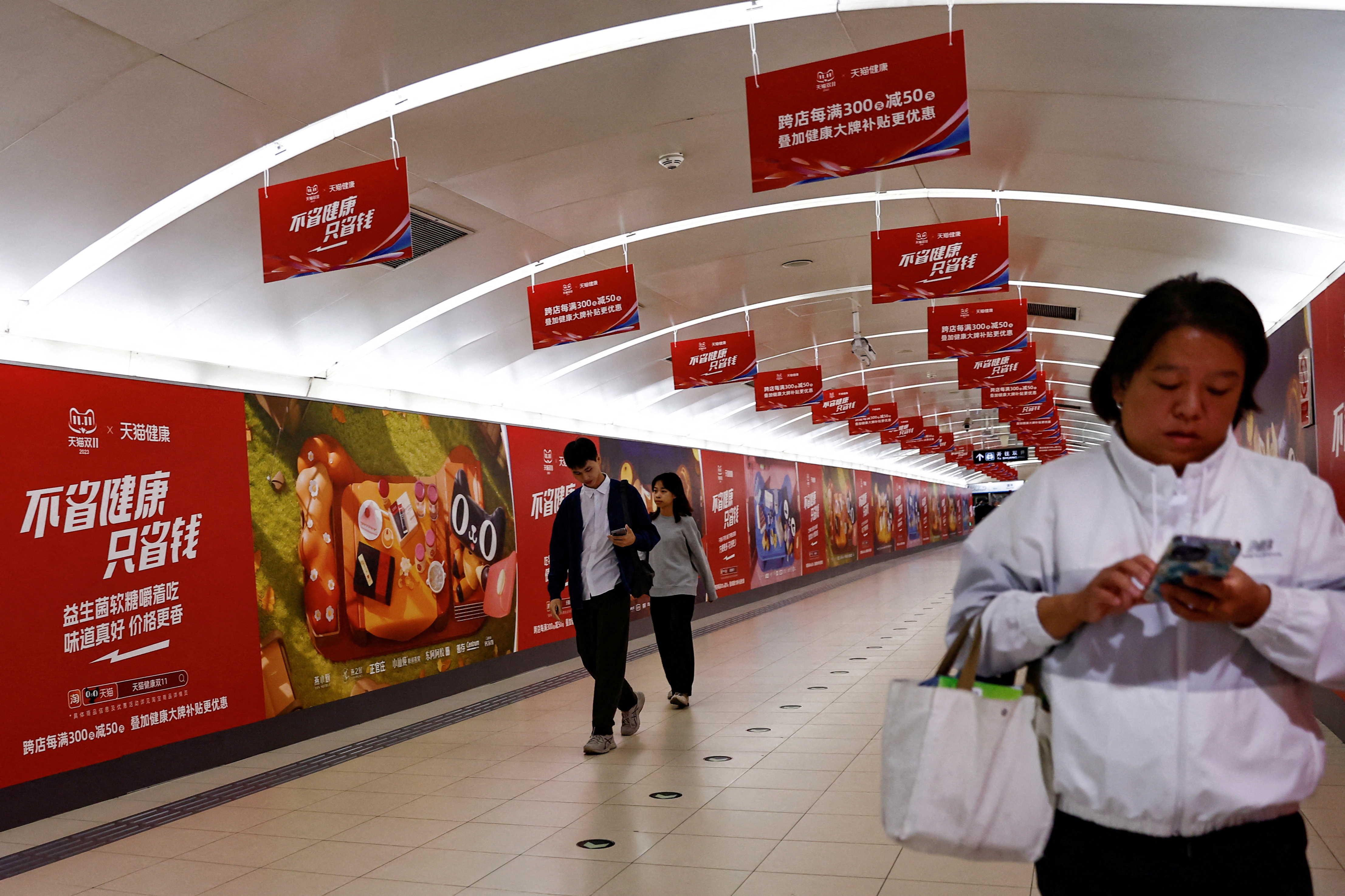 People walk past an Alibaba's advertisement promoting Singles Day shopping festival, in Beijing
