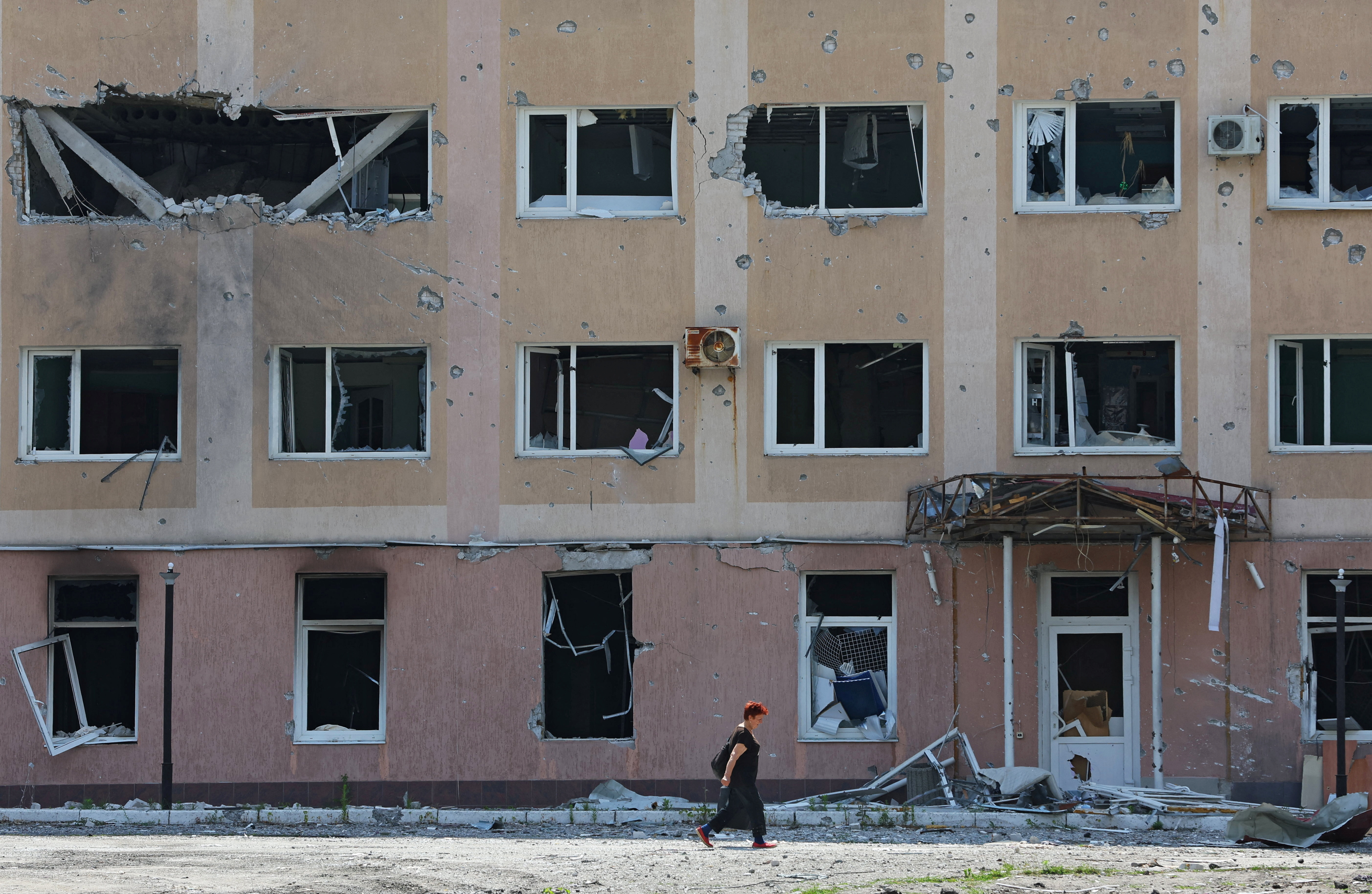 A local resident walks past a damaged building in Lysychansk