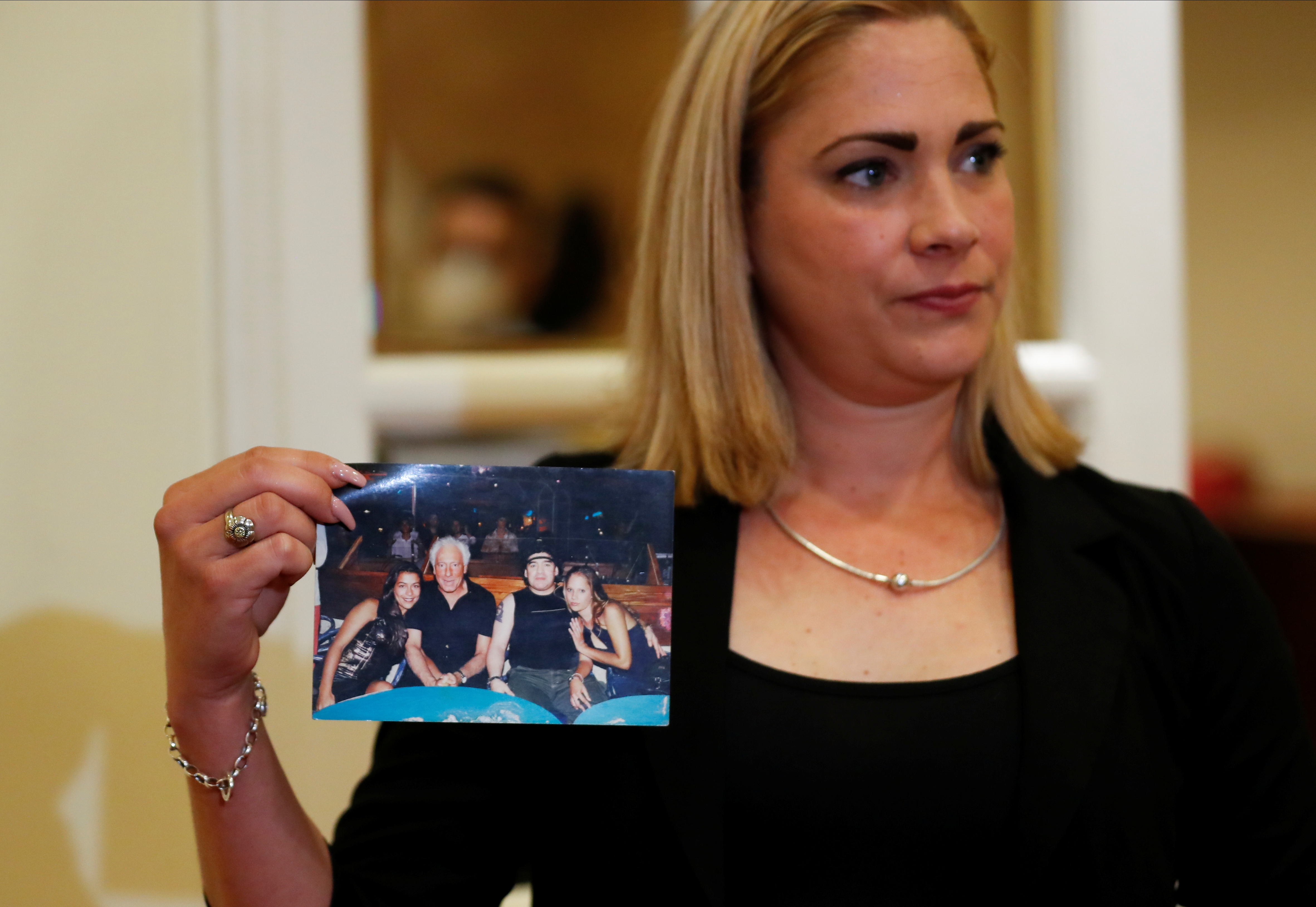 Cuban Mavys Alvarez, who testified against soccer legend Diego Armando Maradona in a case for alleged human trafficking, holds a picture of her sitting next to Maradona, his former agent Guillermo Coppola and an unidentified woman, after a news conference with foreign media, in Buenos Aires, Argentina November 22, 2021. REUTERS/Agustin Marcarian NO RESALES. NO ARCHIVES