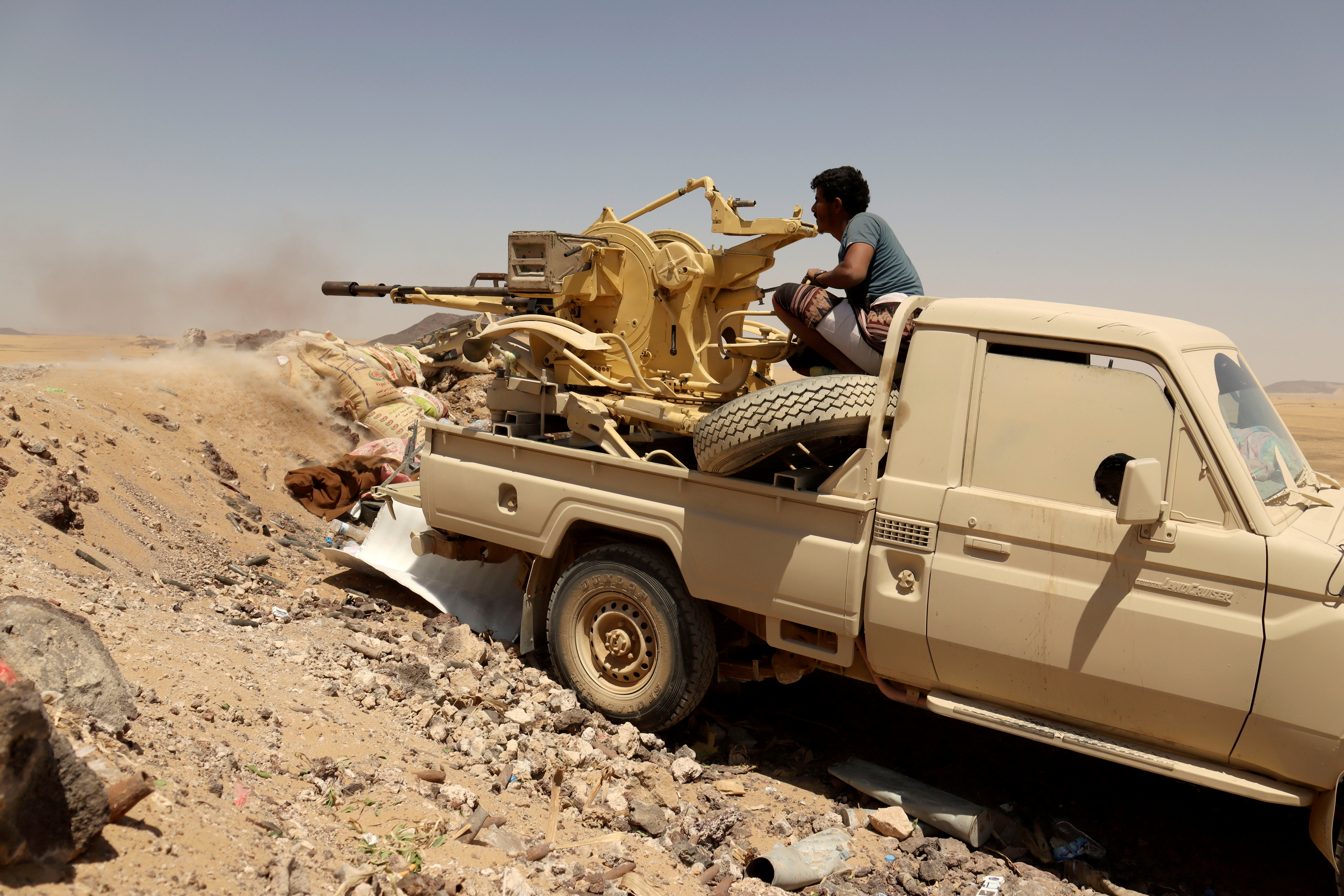 A Yemeni government fighter fires a vehicle-mounted weapon at a frontline position during fighting against Houthi fighters in Marib