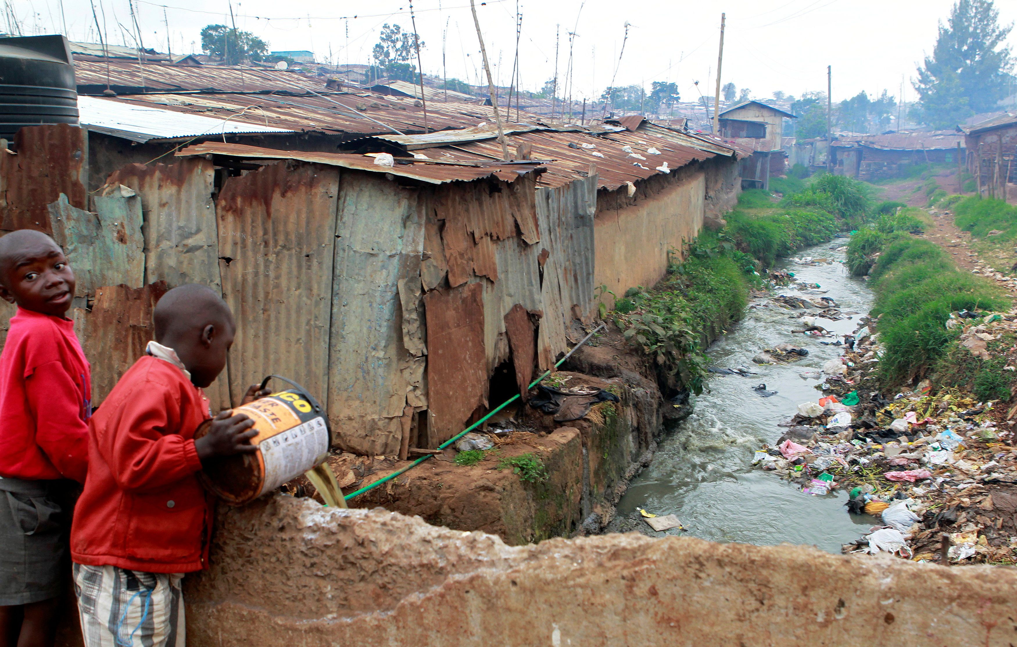 A boy disposes of raw sewage into a stream in the sprawling Kibera slum in Kenya's capital Nairobi