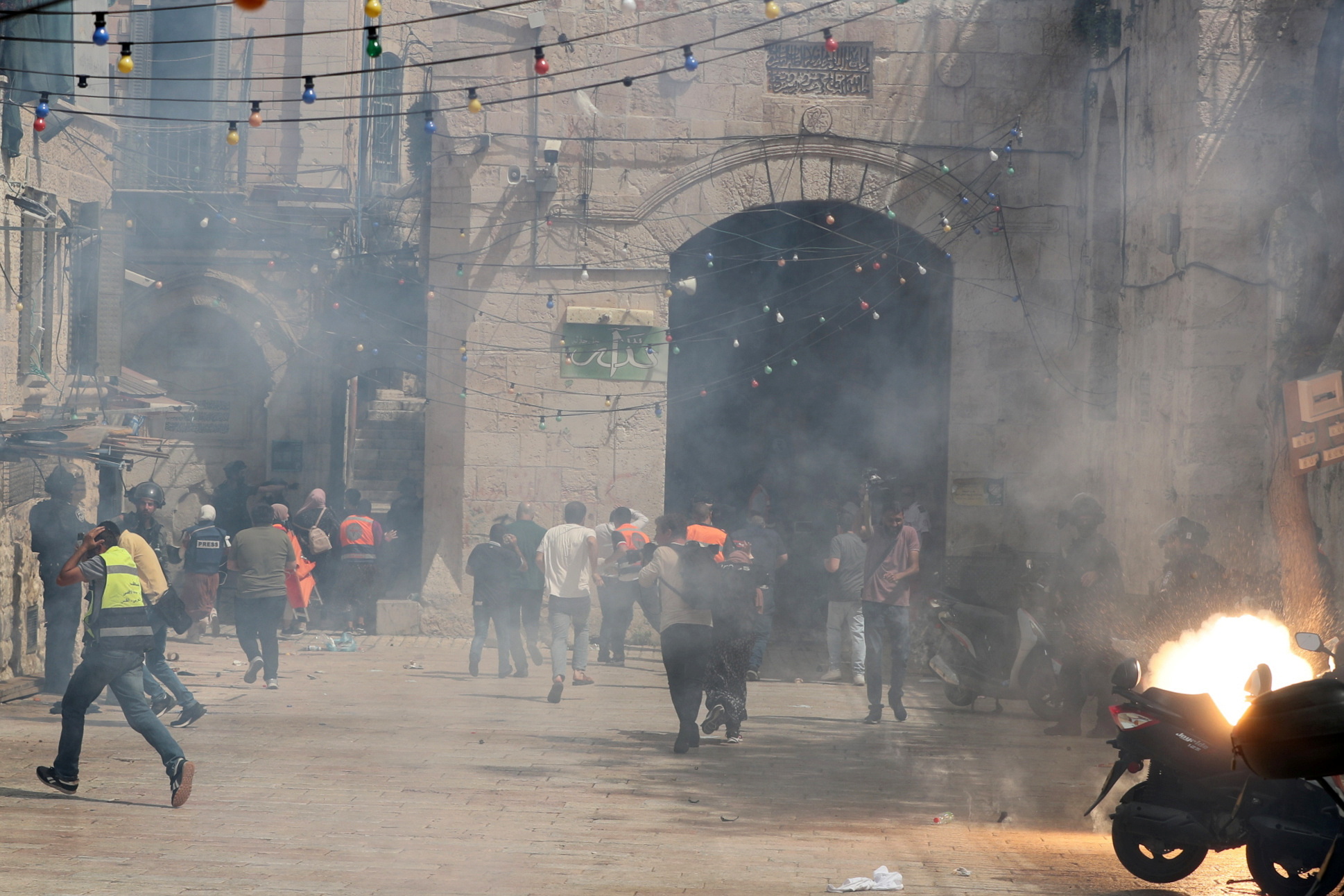 Palestinians run away as Israeli police fire a stun grenade during clashes at the compound that houses Al-Aqsa Mosque, known to Muslims as Noble Sanctuary and to Jews as Temple Mount, in Jerusalem's Old City, May 10, 2021. REUTERS/Ammar Awad