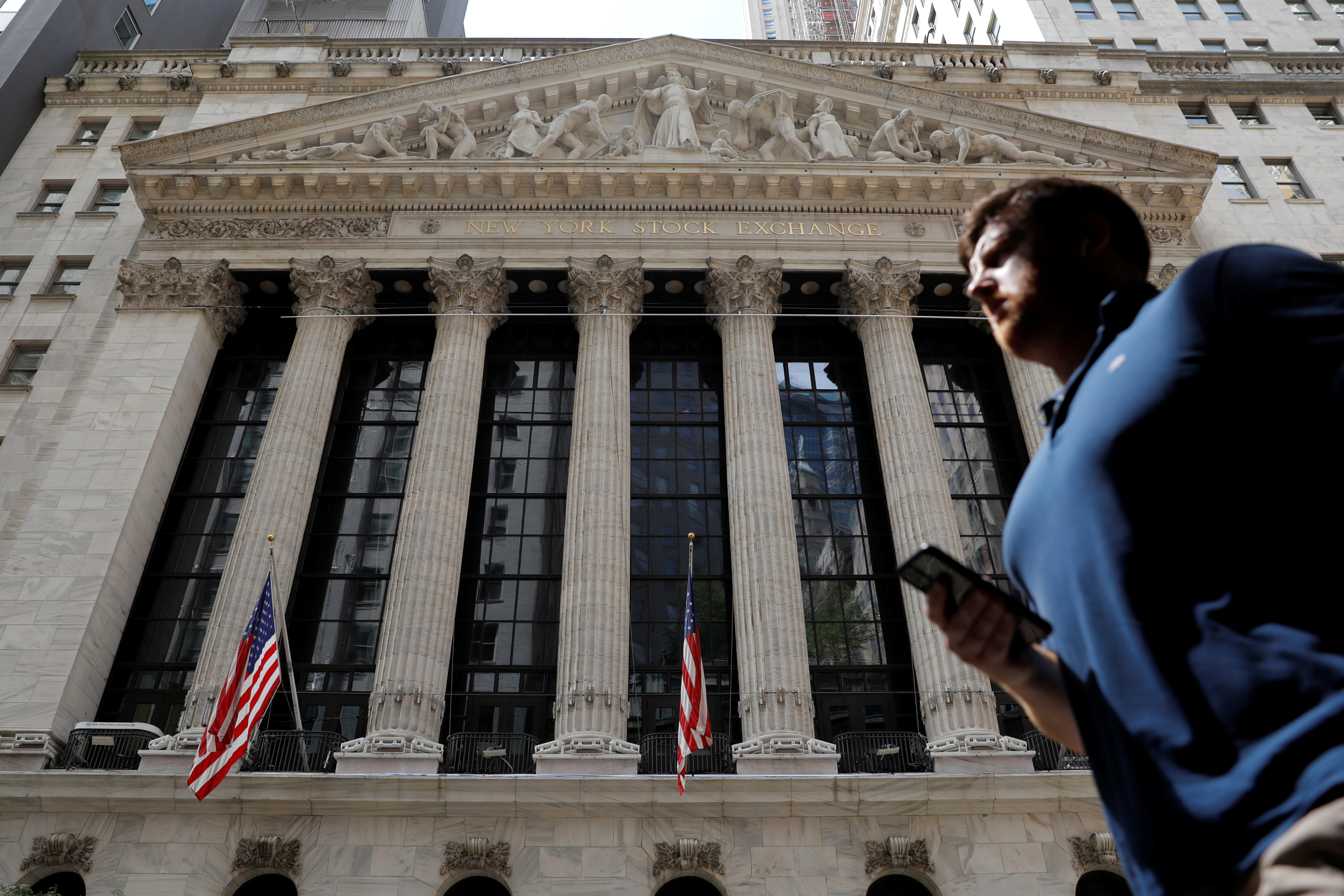A person walks by the New York Stock Exchange (NYSE) in New York City, New York, U.S., July 19, 2021. REUTERS/Andrew Kelly