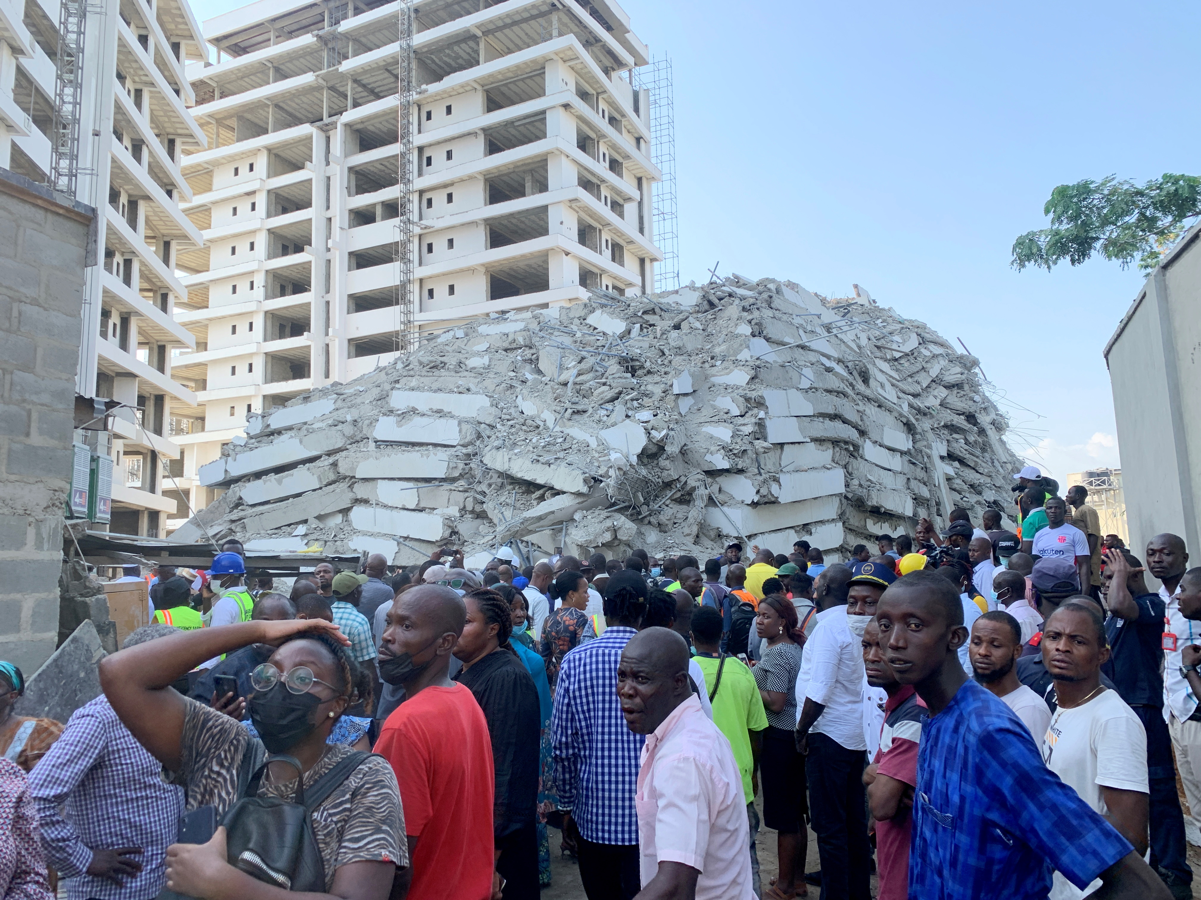 People gather at the site of a collapsed 21-story building in Ikoyi, Lagos