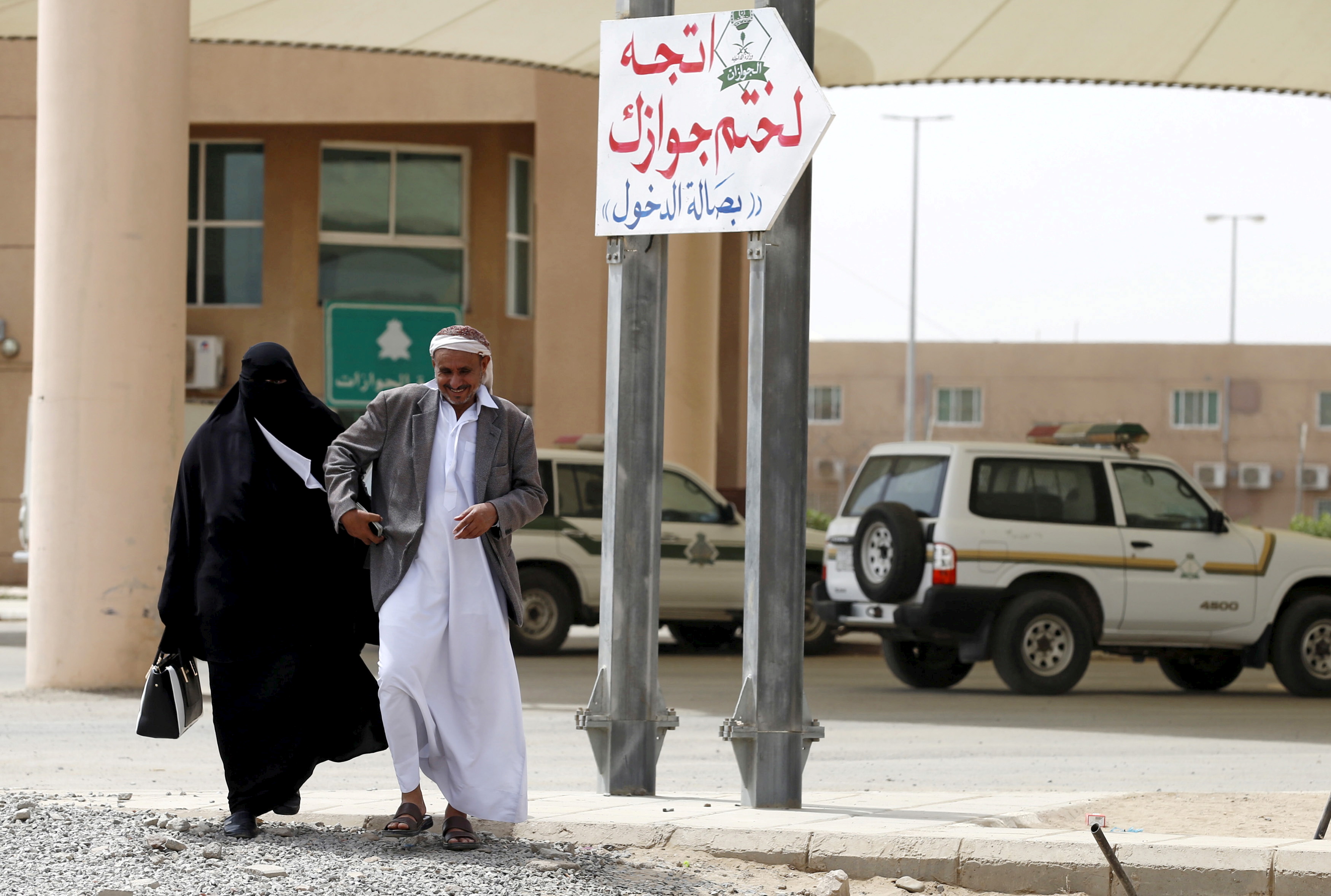 Yemeni man walks with his wife as they arrive to stamp their passports to enter Saudi Arabia at Al-Tiwal crossing in Jizan on Saudi Arabia's border with Yemen