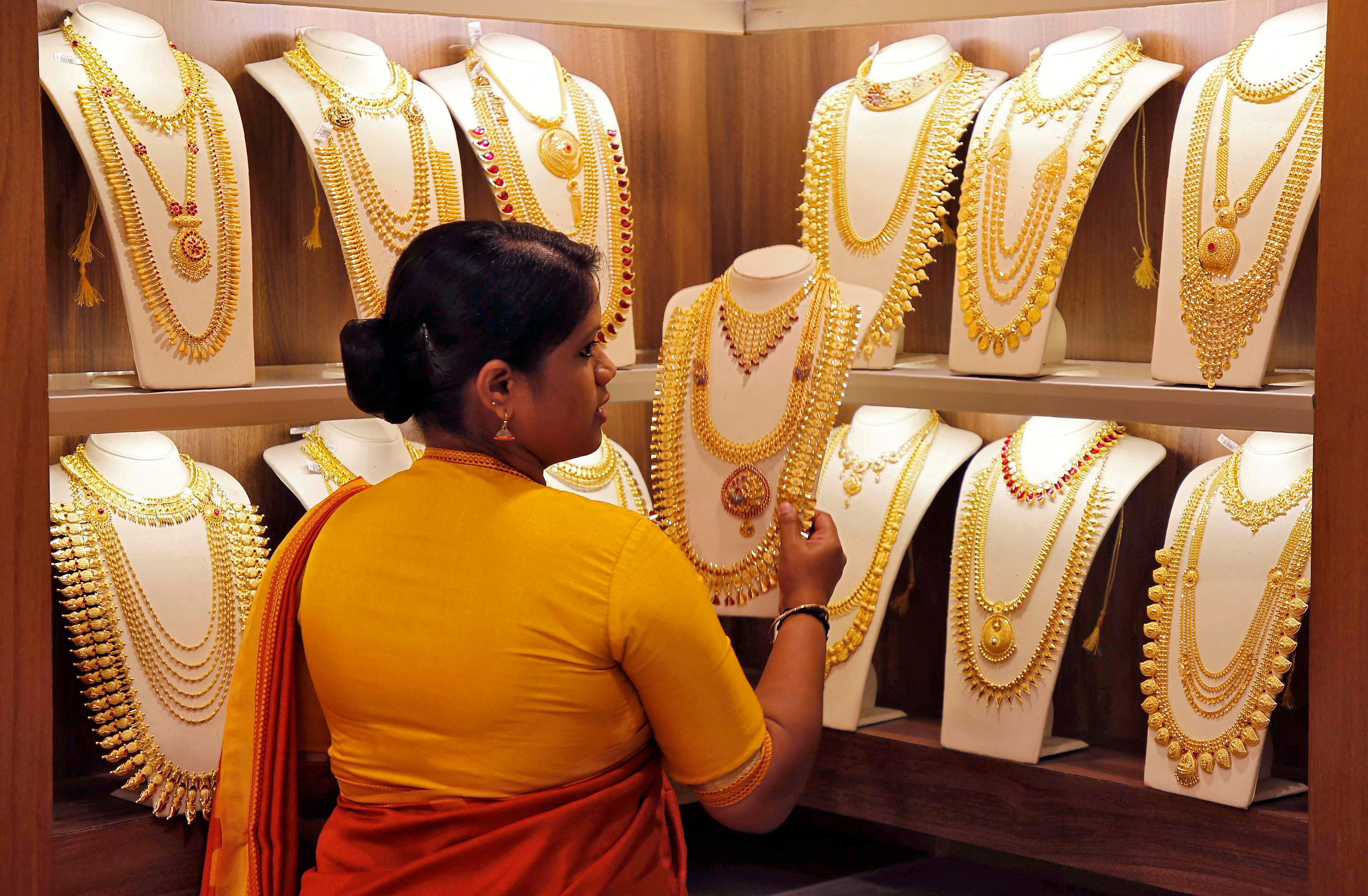 A saleswoman picks gold necklaces to show it to a customer inside a jewellery showroom on the occasion of Akshaya Tritiya, a major gold buying festival, in Kochi