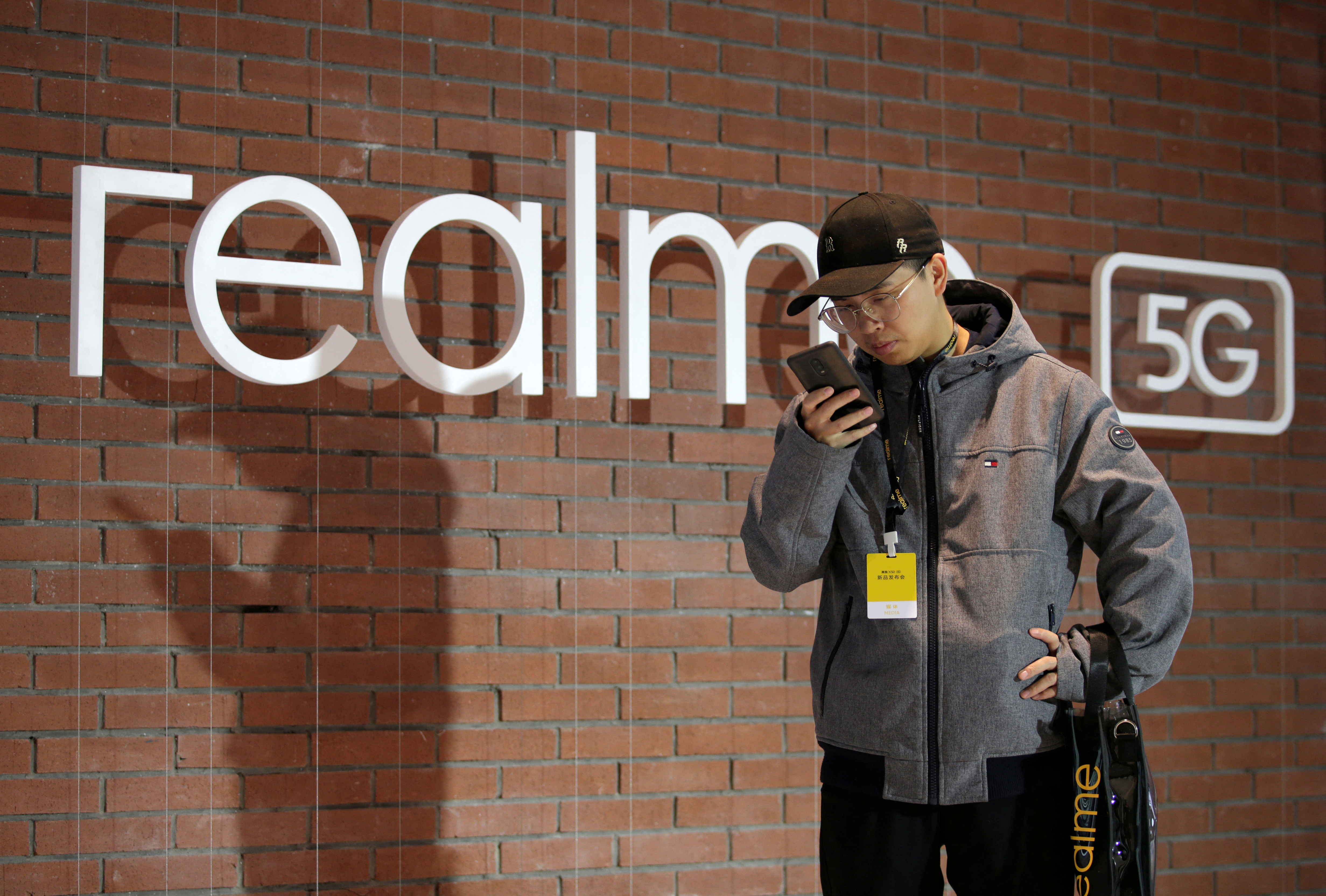 Man looks at mobile phone next to Realme logo during product launch event of X50 5G in Beijing
