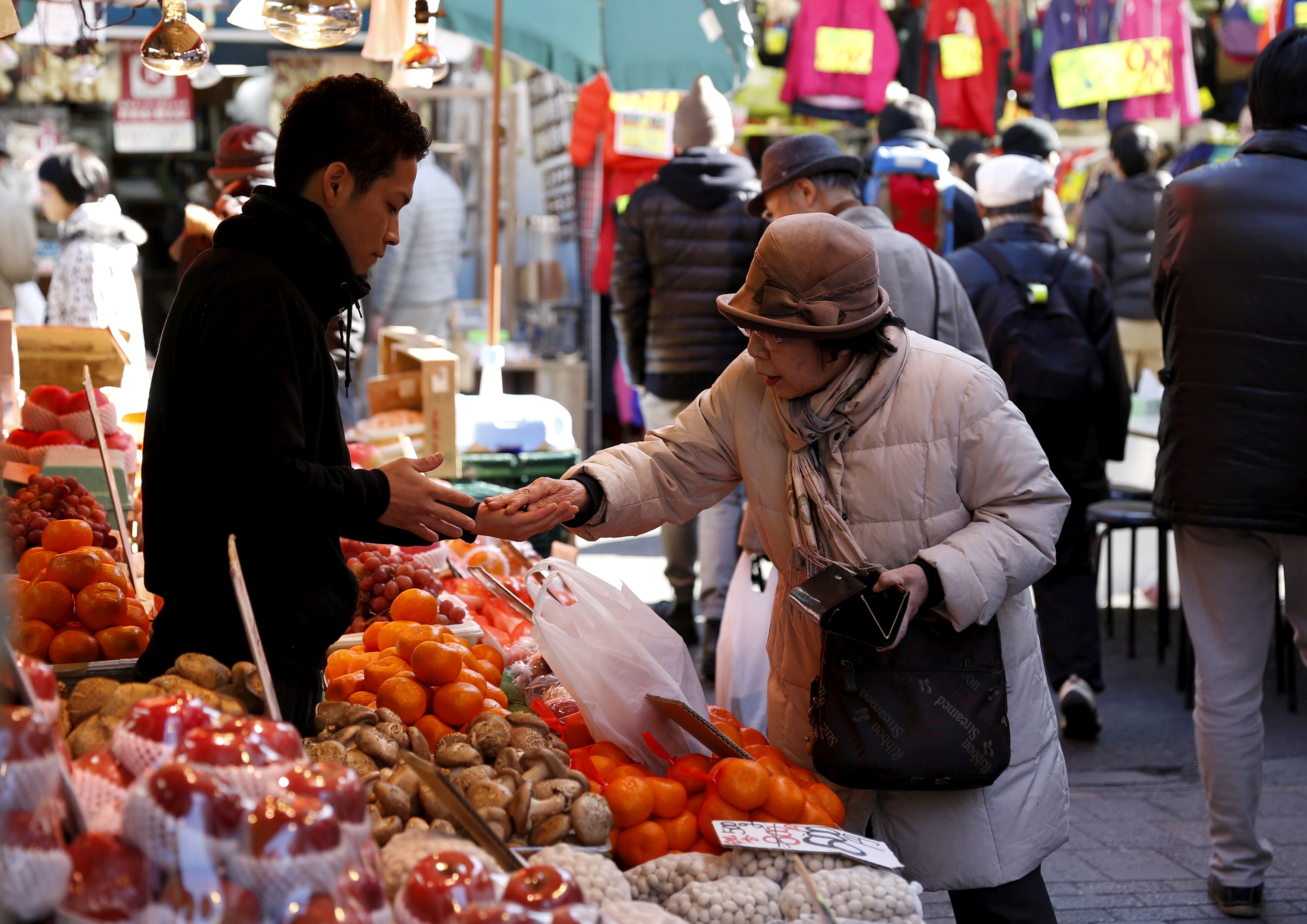 A woman pays money as she buys fruits outside a vegetable store at Ameyoko shopping district in Tokyo