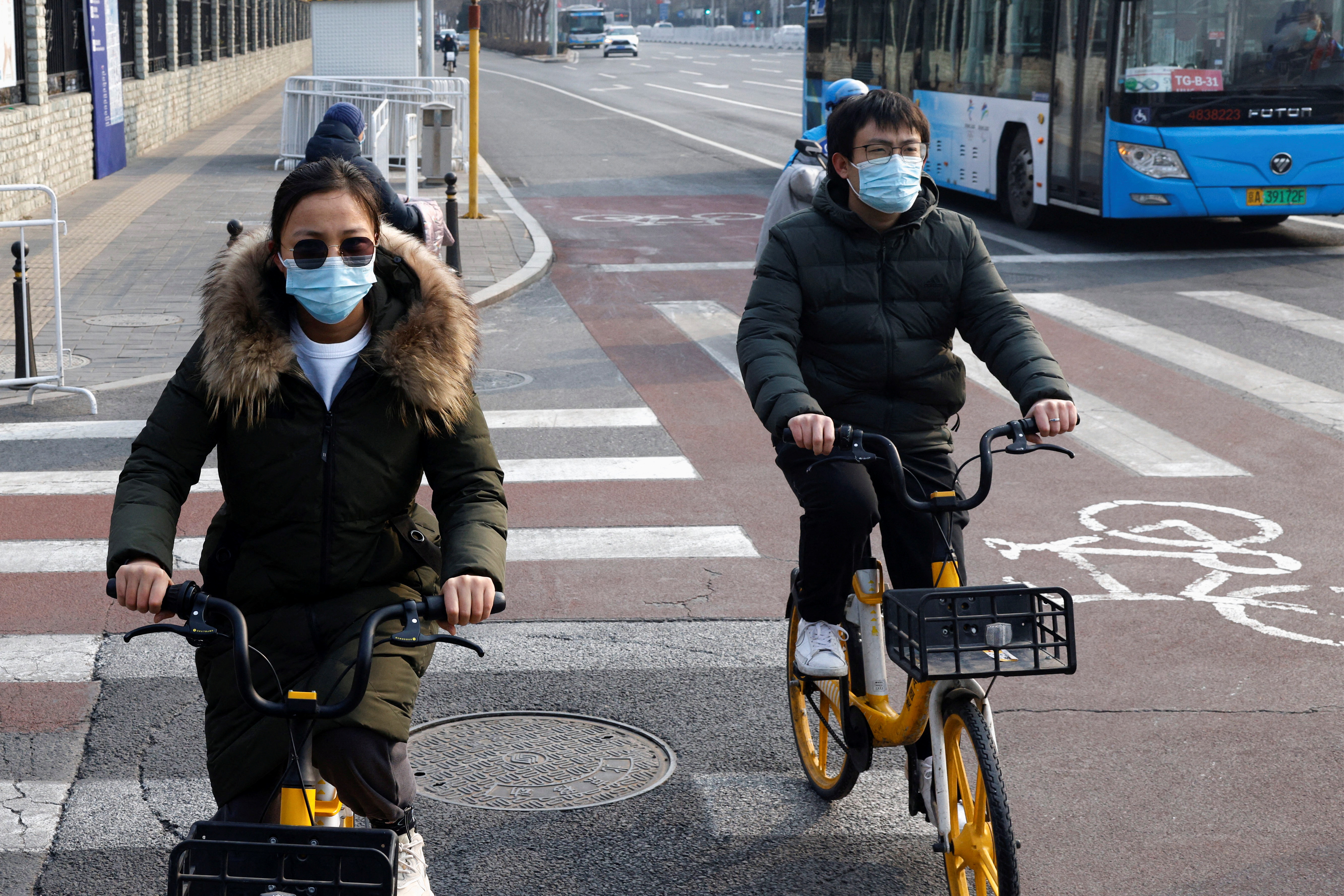 People wearing protective masks ride bicycles in Beijing