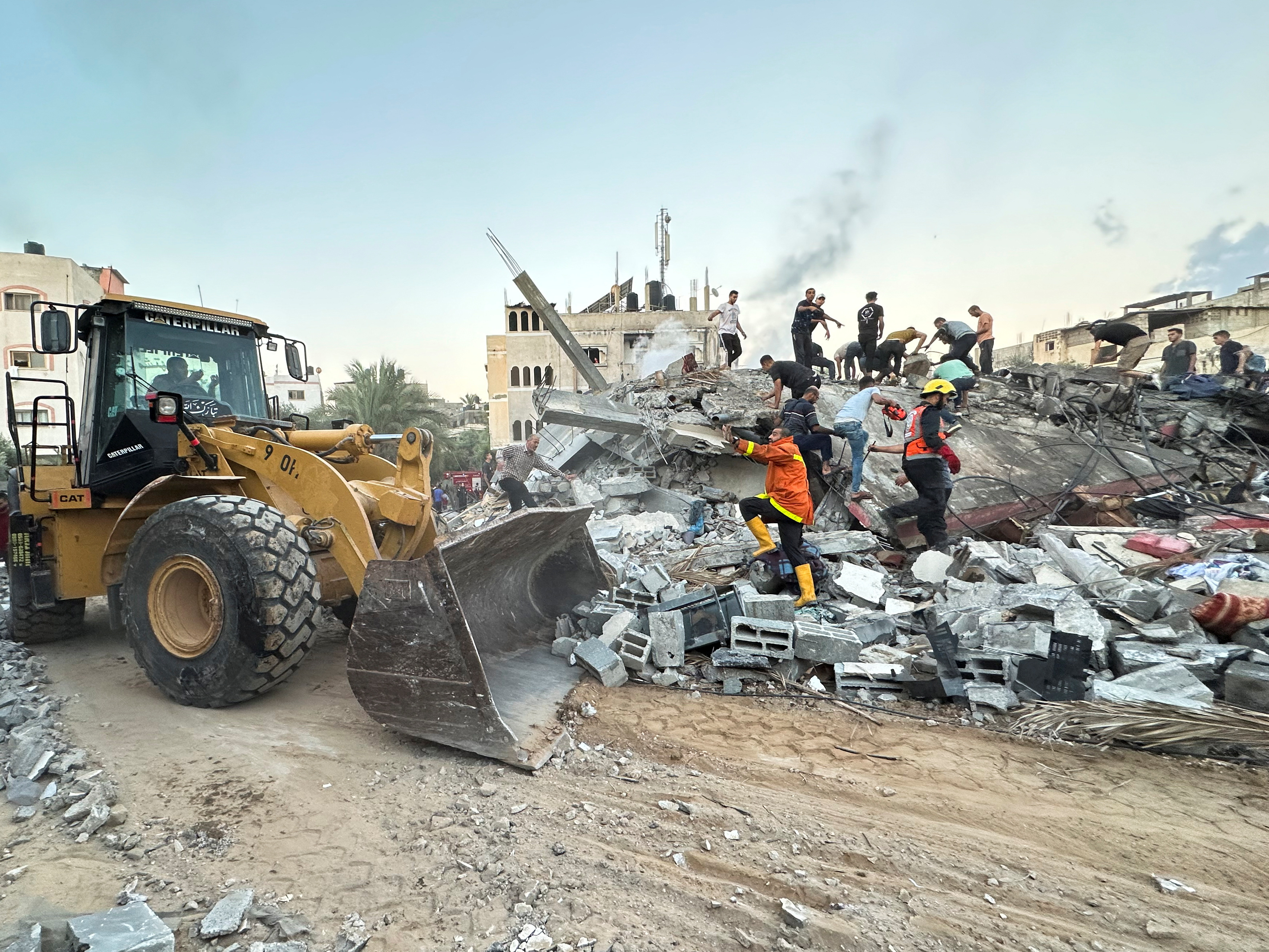 Palestinians work to remove the debris as they search for casualties under the rubble of a house destroyed by Israeli strikes, in the central Gaza Strip