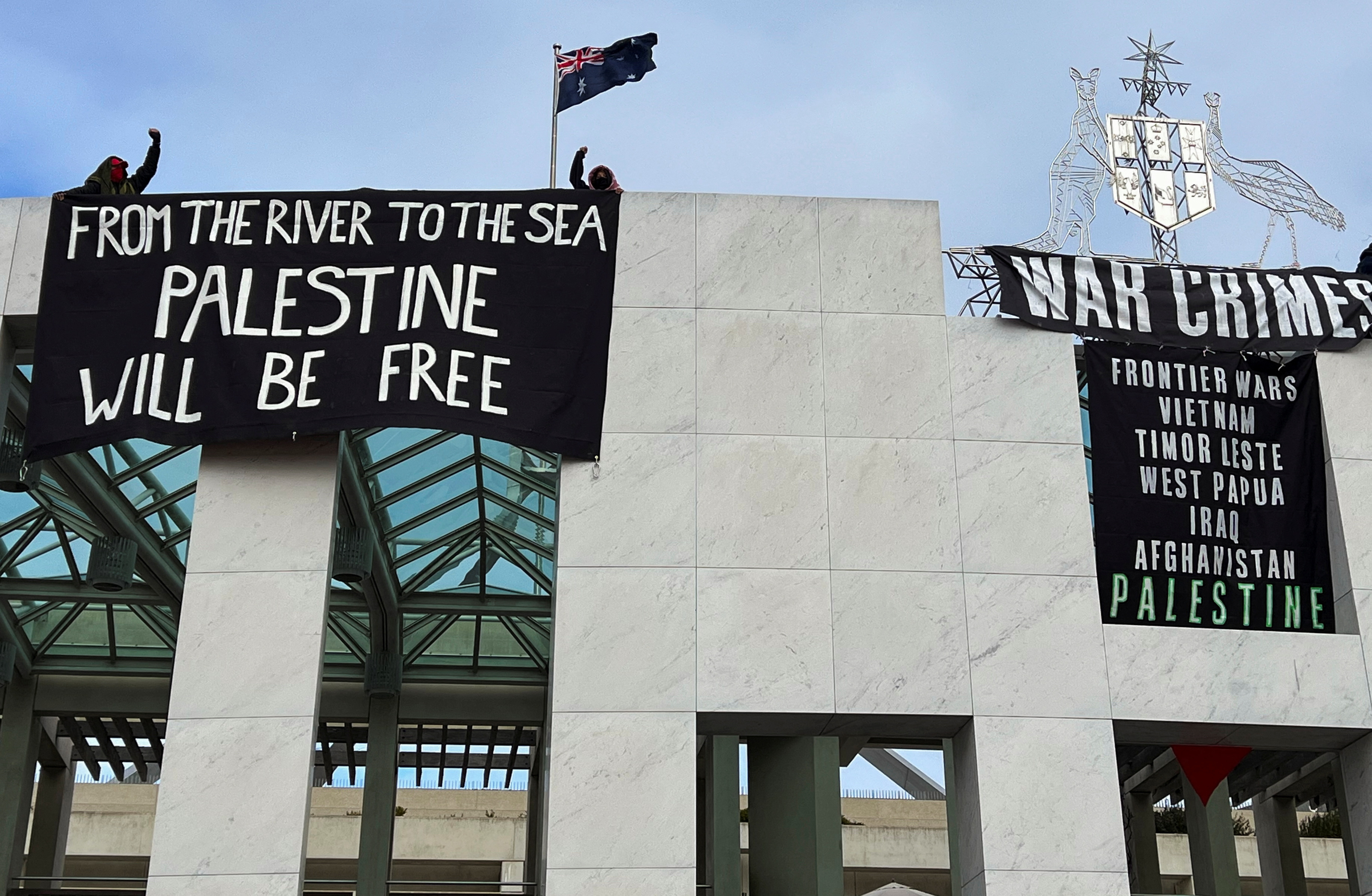 Pro-Palestinian protesters hang banners at the Parliament House in Canberra