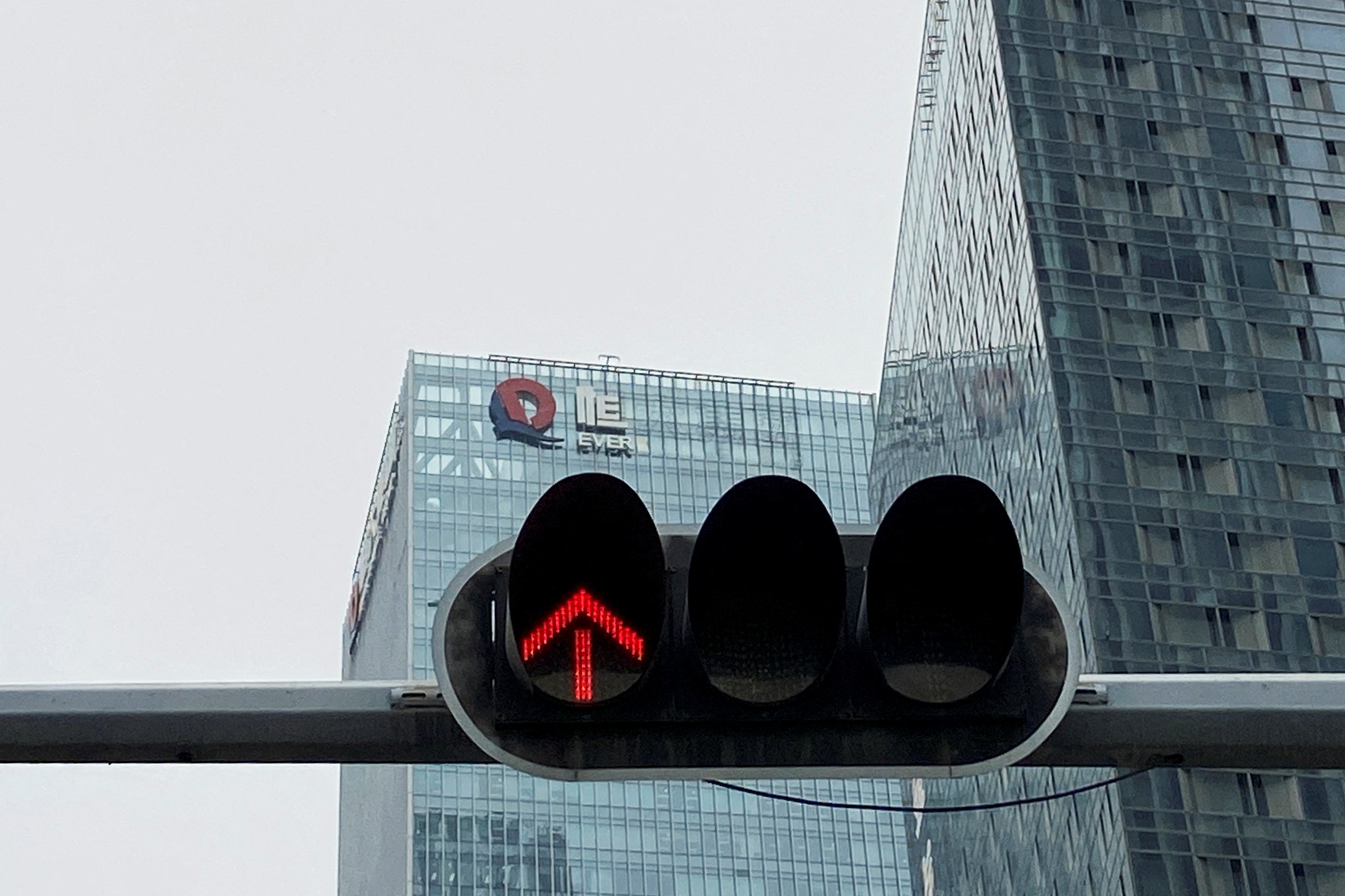 A partially removed company logo of China Evergrande Group is seen on the facade of its headquarters, near a traffic light in Shenzhen, Guangdong province, China January 10, 2022. REUTERS/David Kirton