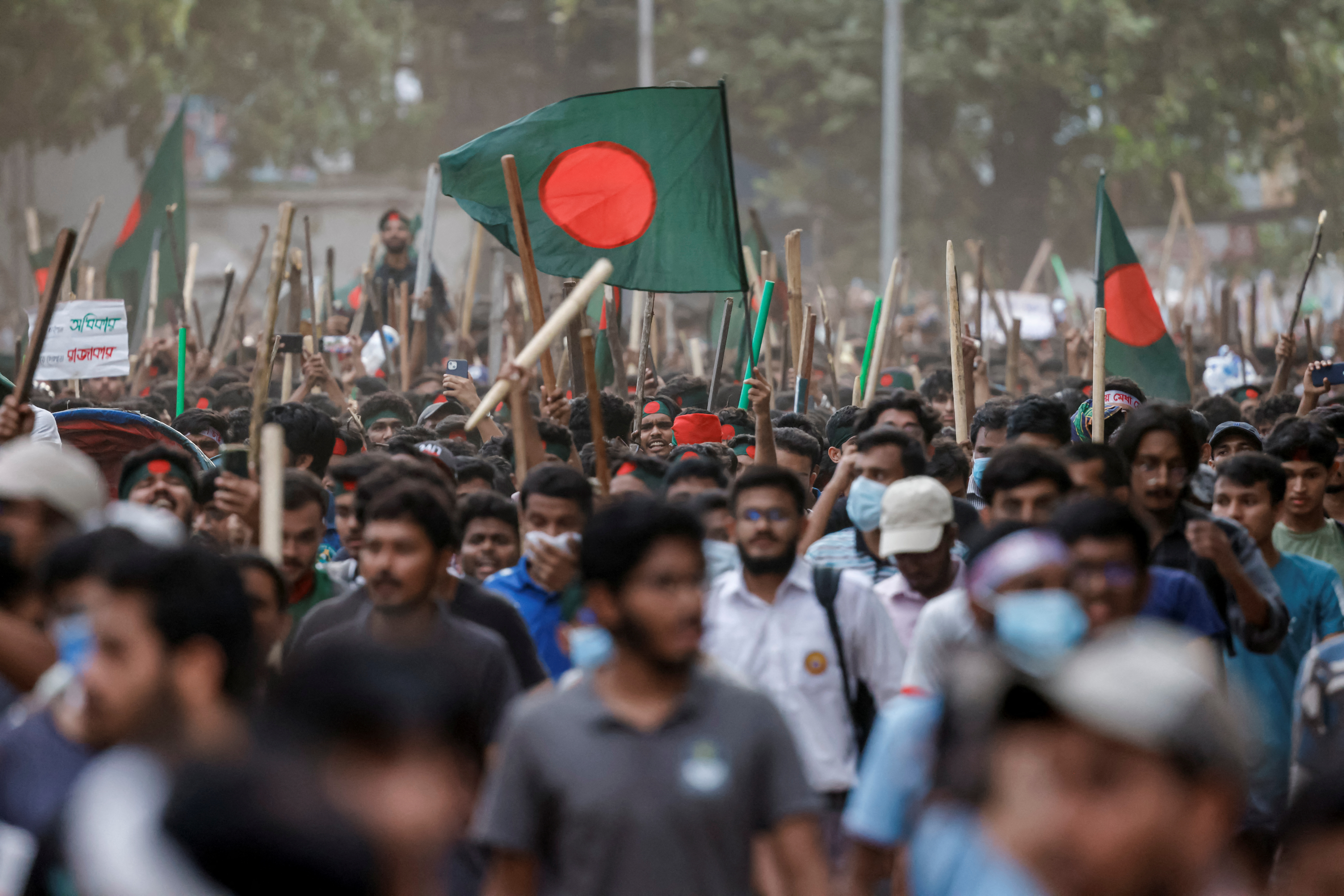 Anti-quota protesters march with Bangladeshi flags and sticks as they engage in a clash with Bangladesh Chhatra League, the student wing of the ruling party Bangladesh Awami League, at the University of Dhaka