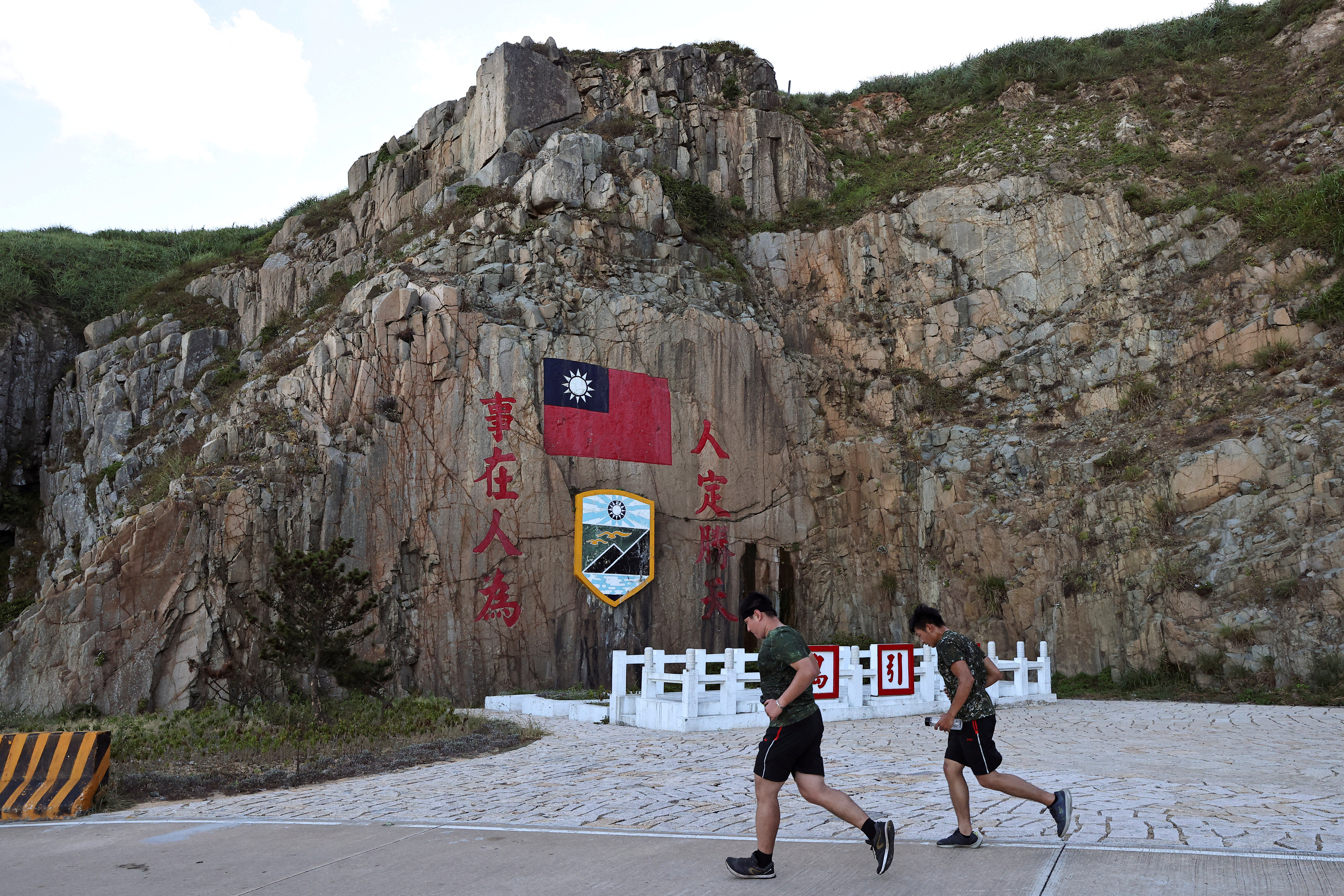 Soldados marchan junto a un letrero de la bandera de Taiwán en la isla de Dongyin
