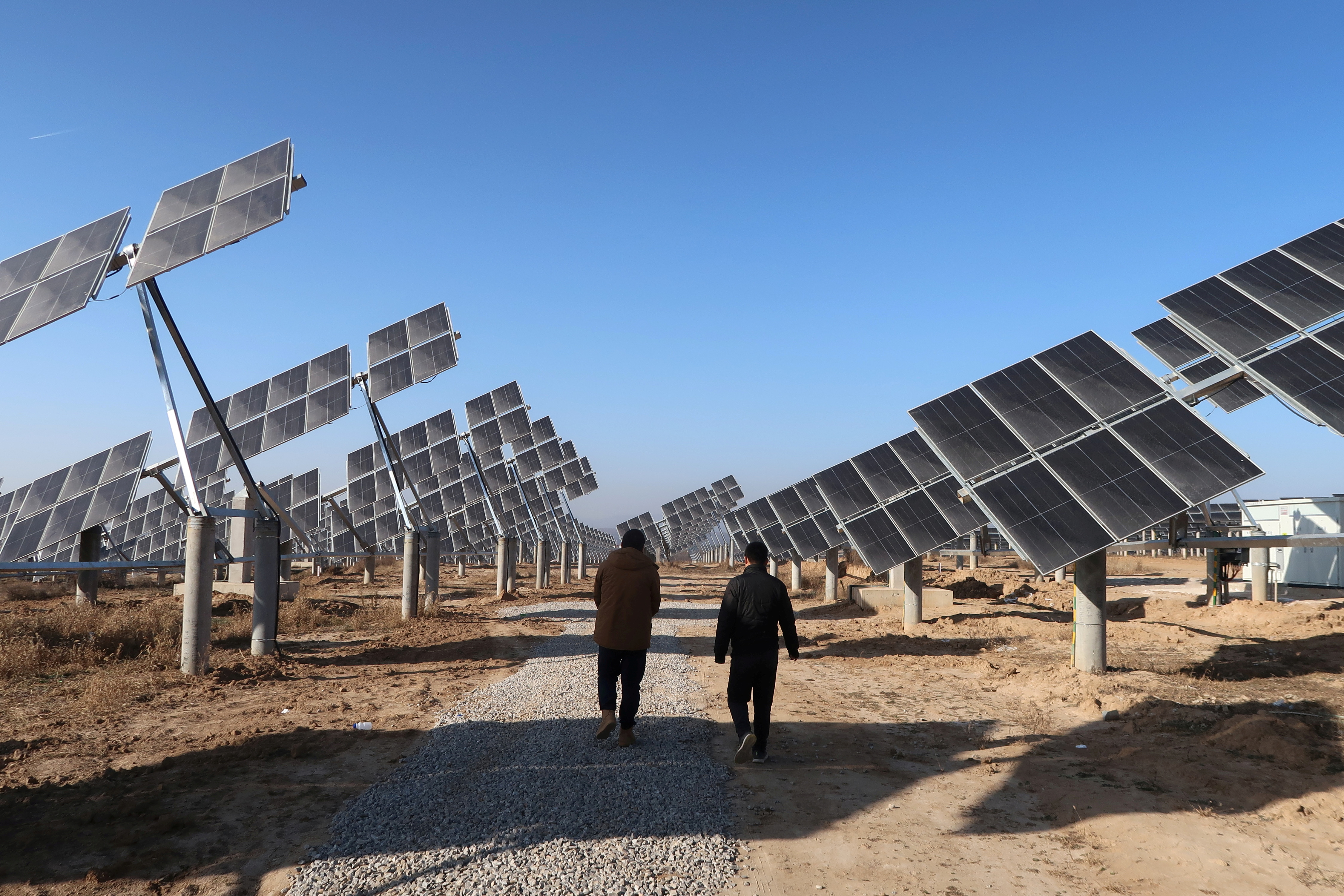 Workers walk at a solar power station in Tongchuan, Shaanxi