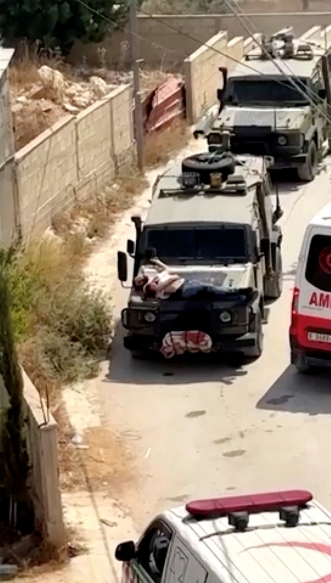 Israeli army straps wounded Palestinian on military jeep during raid, in Jenin