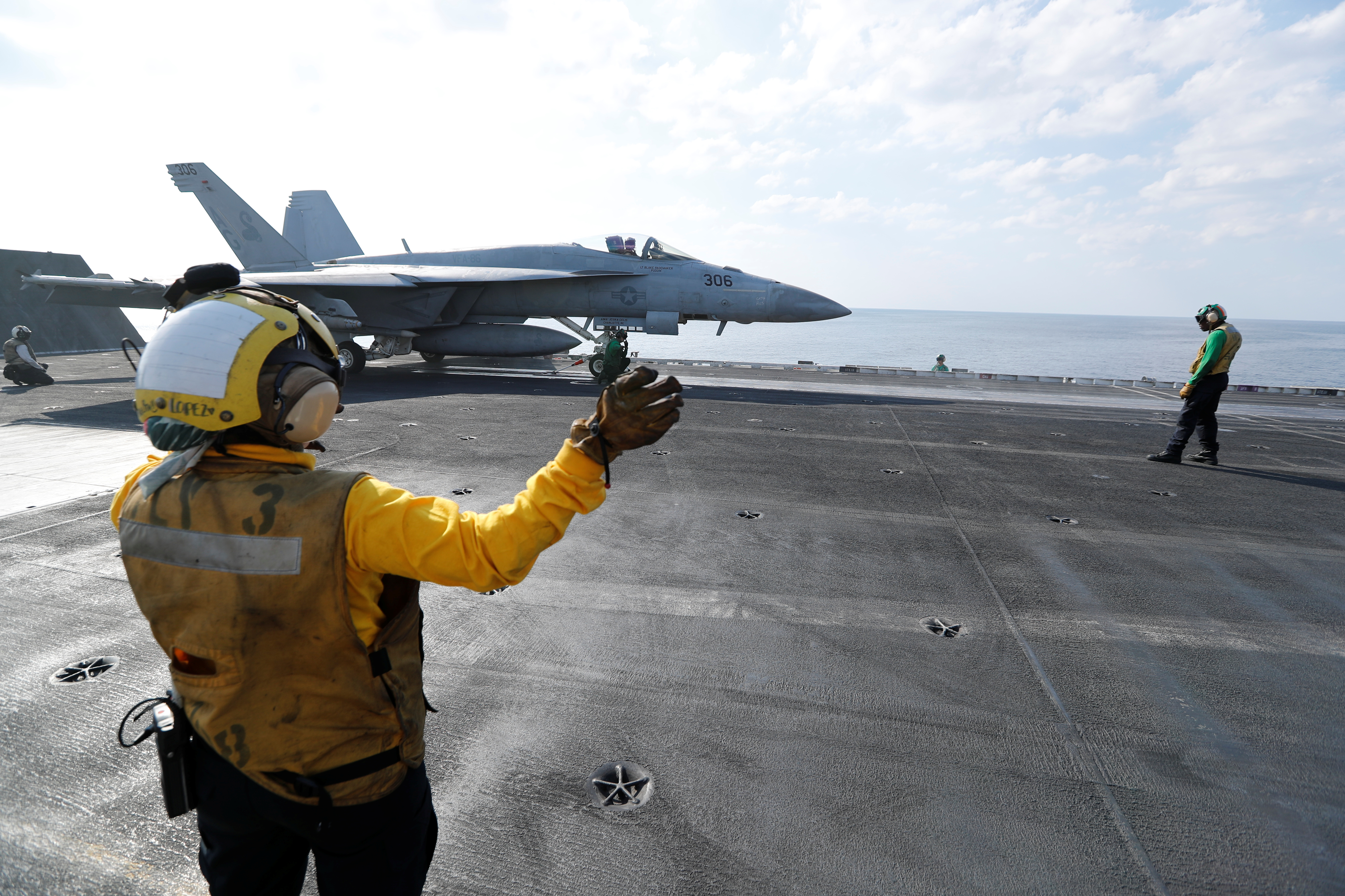 Shooter and Controler prepare an F/A-18E Super Hornet to be catapulted off from the flight deck of the aircraft carrier USS Abraham Lincoln in the Gulf