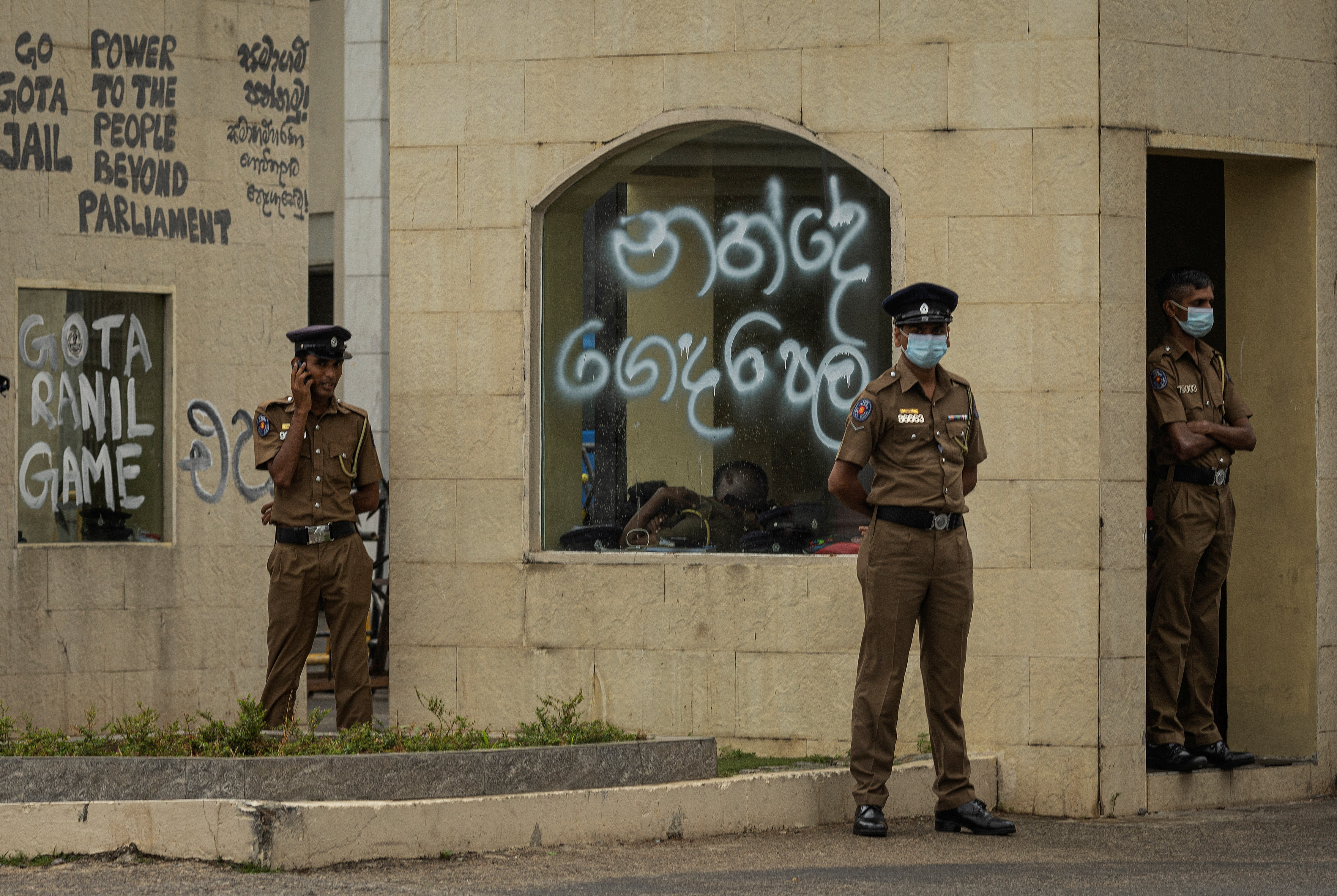 Policemen stand guard next to graffitied wall near the President's House, amid the country's economic crisis, in Colombo